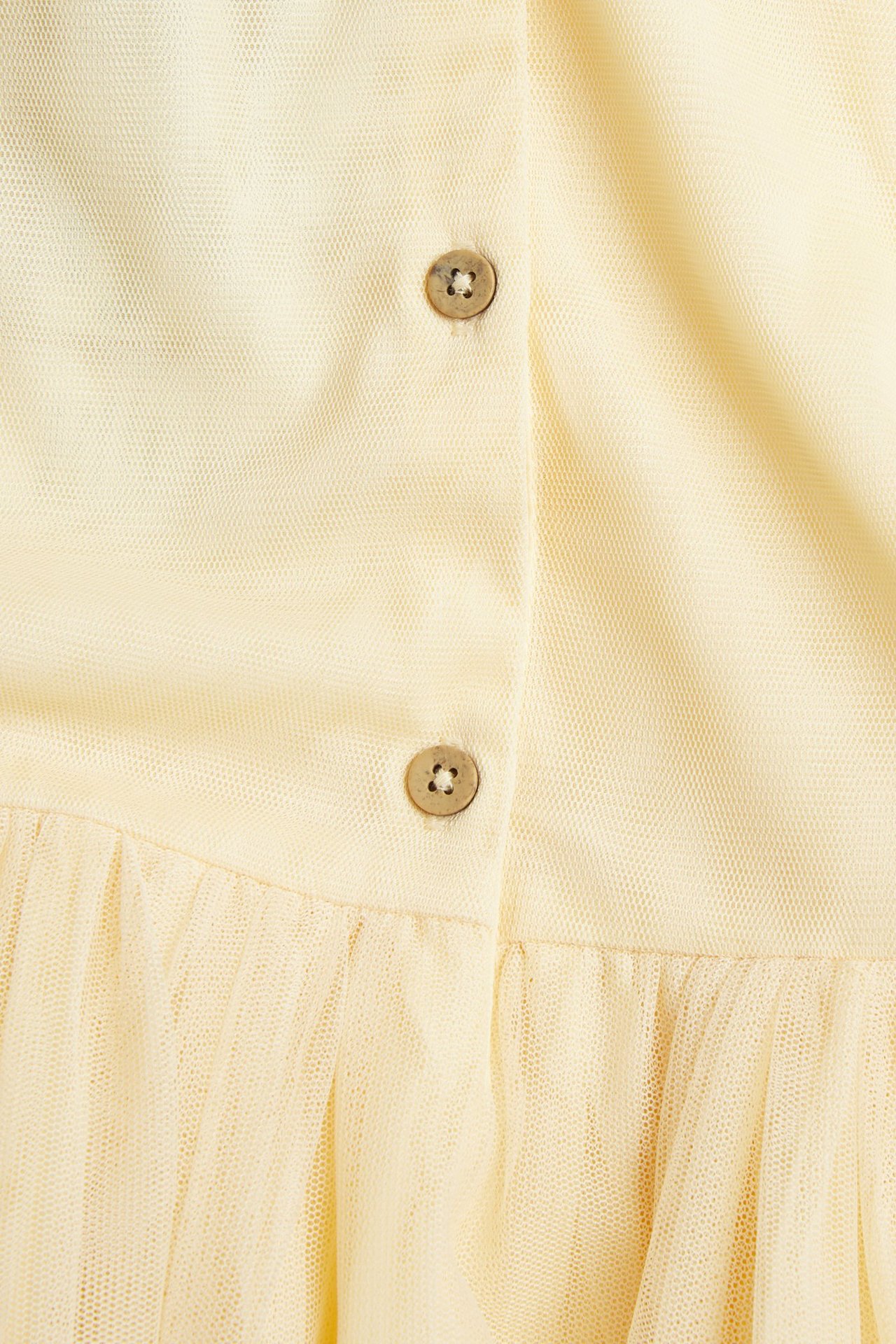 Close-up back view of a yellow mesh dress with two brown buttons above a gathered mesh skirt.