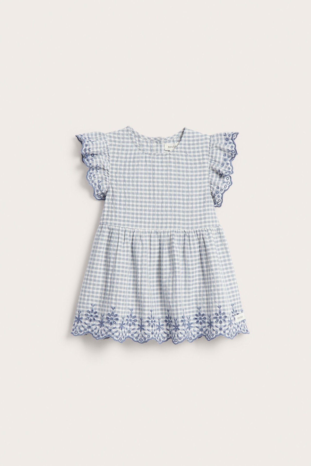 Front view of a kid's blue gingham cotton peplum blouse with ruffled sleeves and embroidered edges.