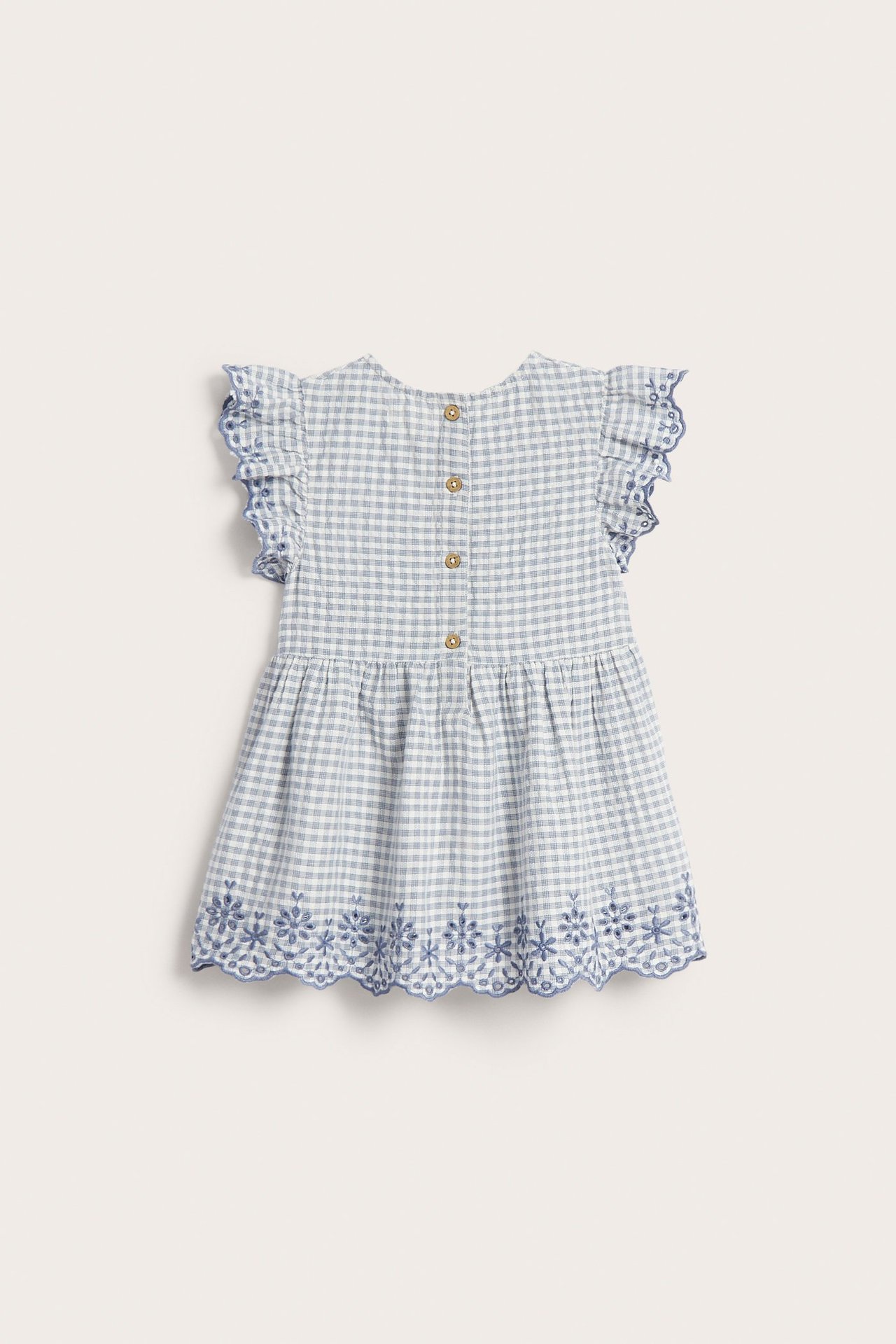 Back view: Child's blue-white checked cotton peplum blouse with ruffled sleeves, back buttons, and floral embroidery.
