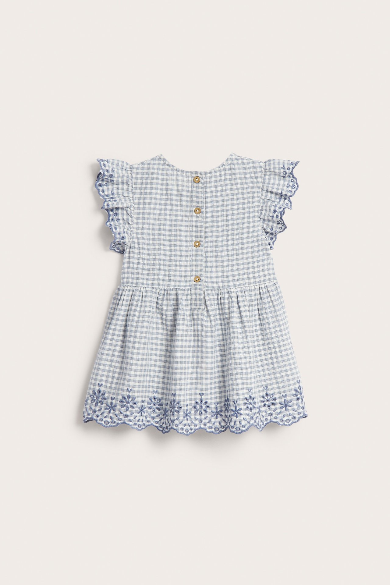 Back view: Kid's light blue checked peplum blouse with ruffled sleeves, buttons, and blue floral embroidery.