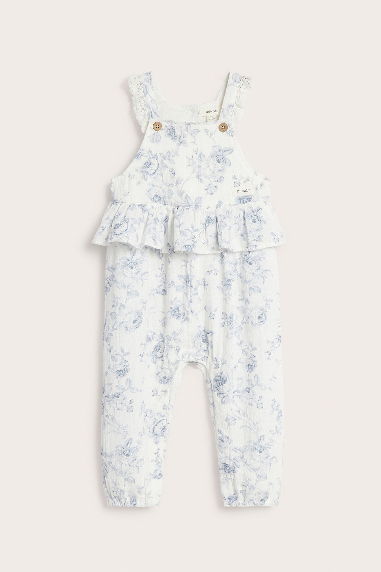 Vorderansicht: Off-white Baby-Blumenoverall mit Taillenrüsche, Spitze und Knopf-Trägern.