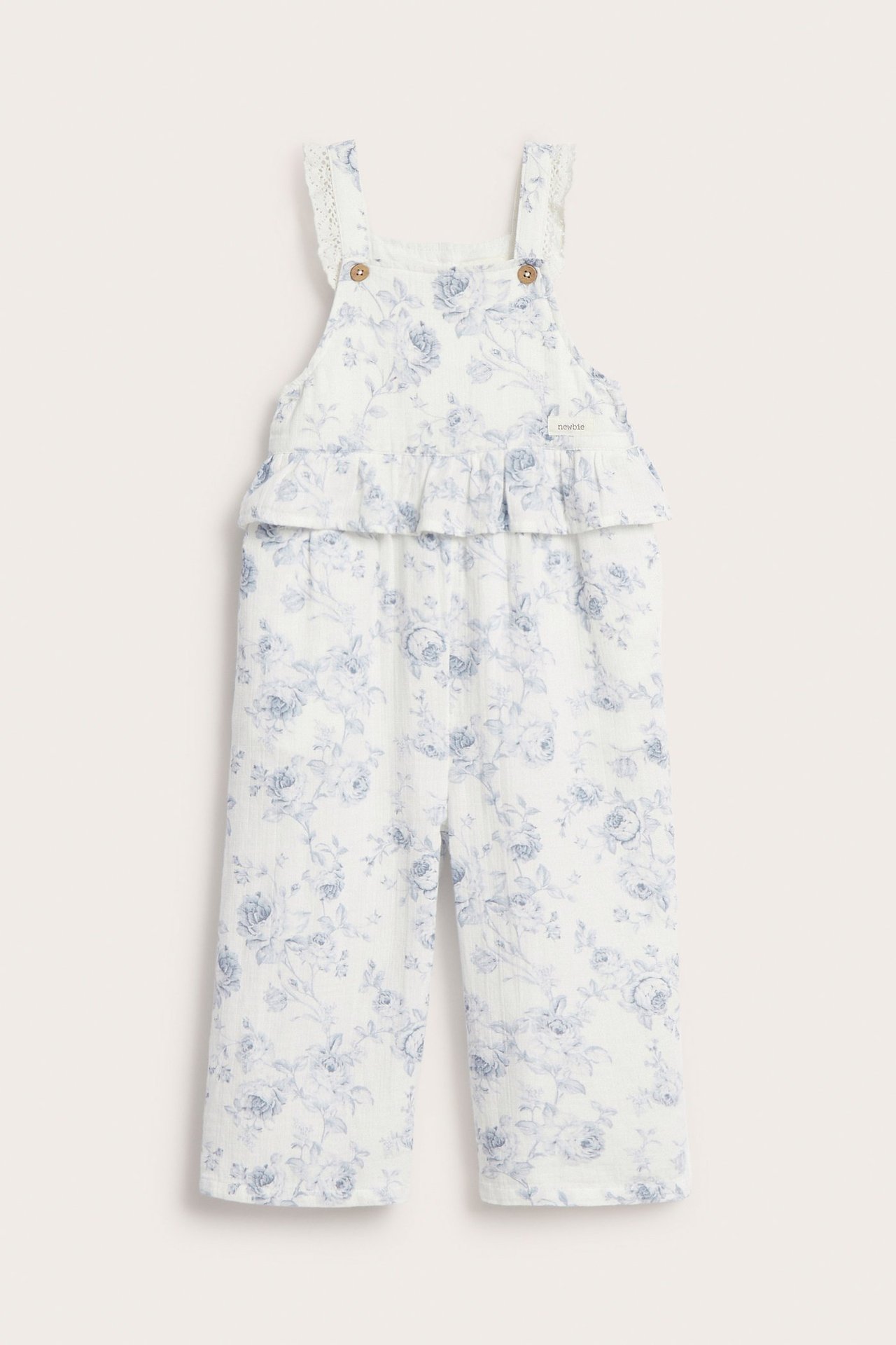 Front view: Off-white cotton kid's floral jumpsuit with waist ruffle and adjustable lace straps.