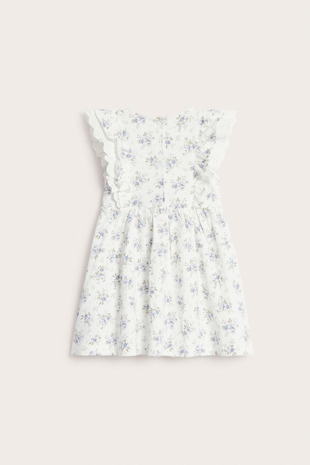 Back view of an off-white kid's floral cotton jersey dress with ruffled lace shoulders and snap buttons.