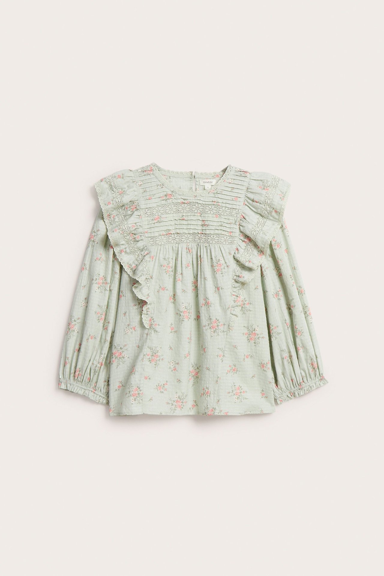 Vorderansicht einer hellgrünen Blumen-Baumwollbluse mit Spitzenrüschen, Biesen und 3/4-Puffärmeln.