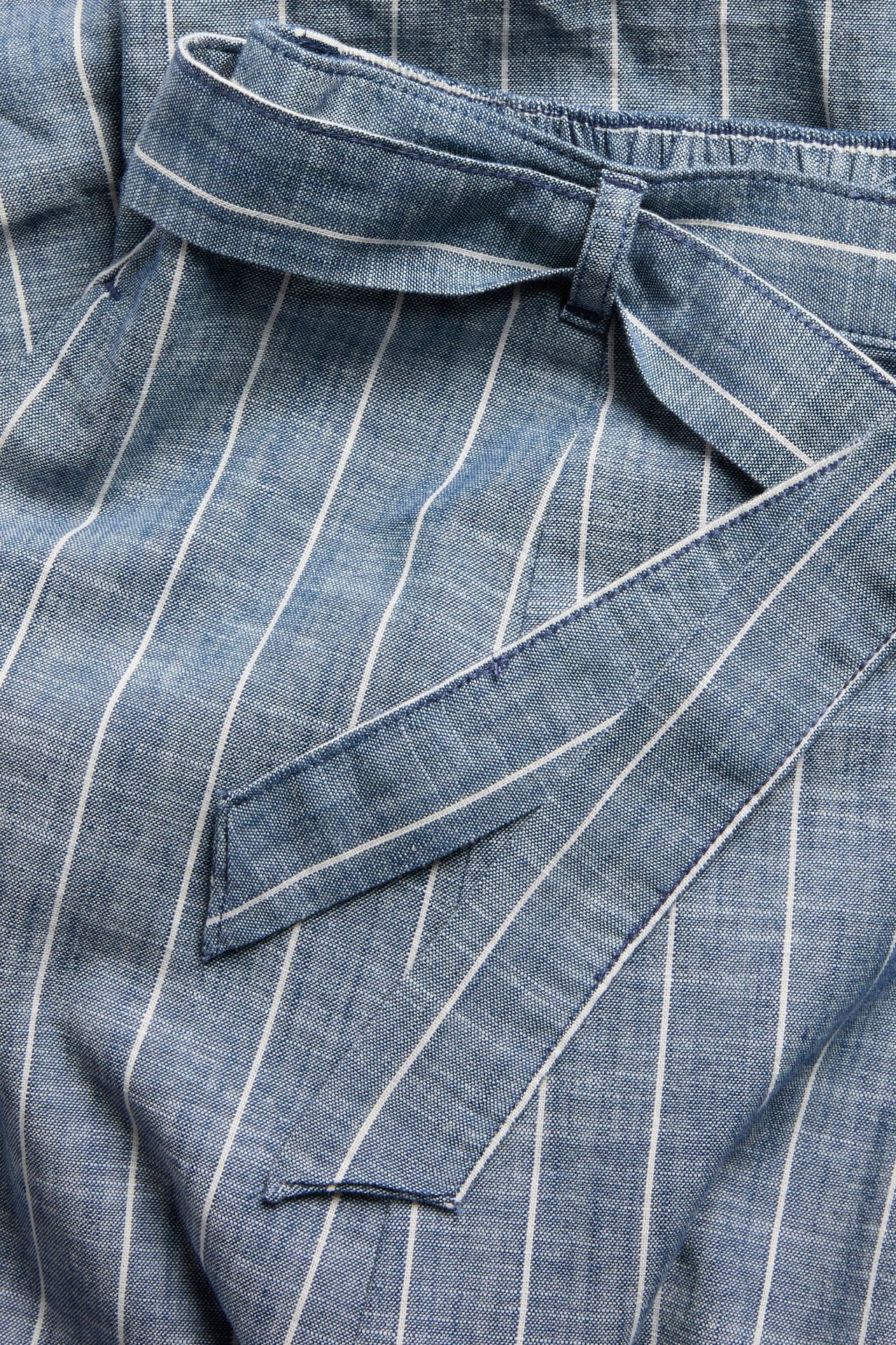 Nahaufnahme: blau-weiß gestreifter Baumwollrock mit Gummibund, gebundenem Gürtel und Seitentasche.