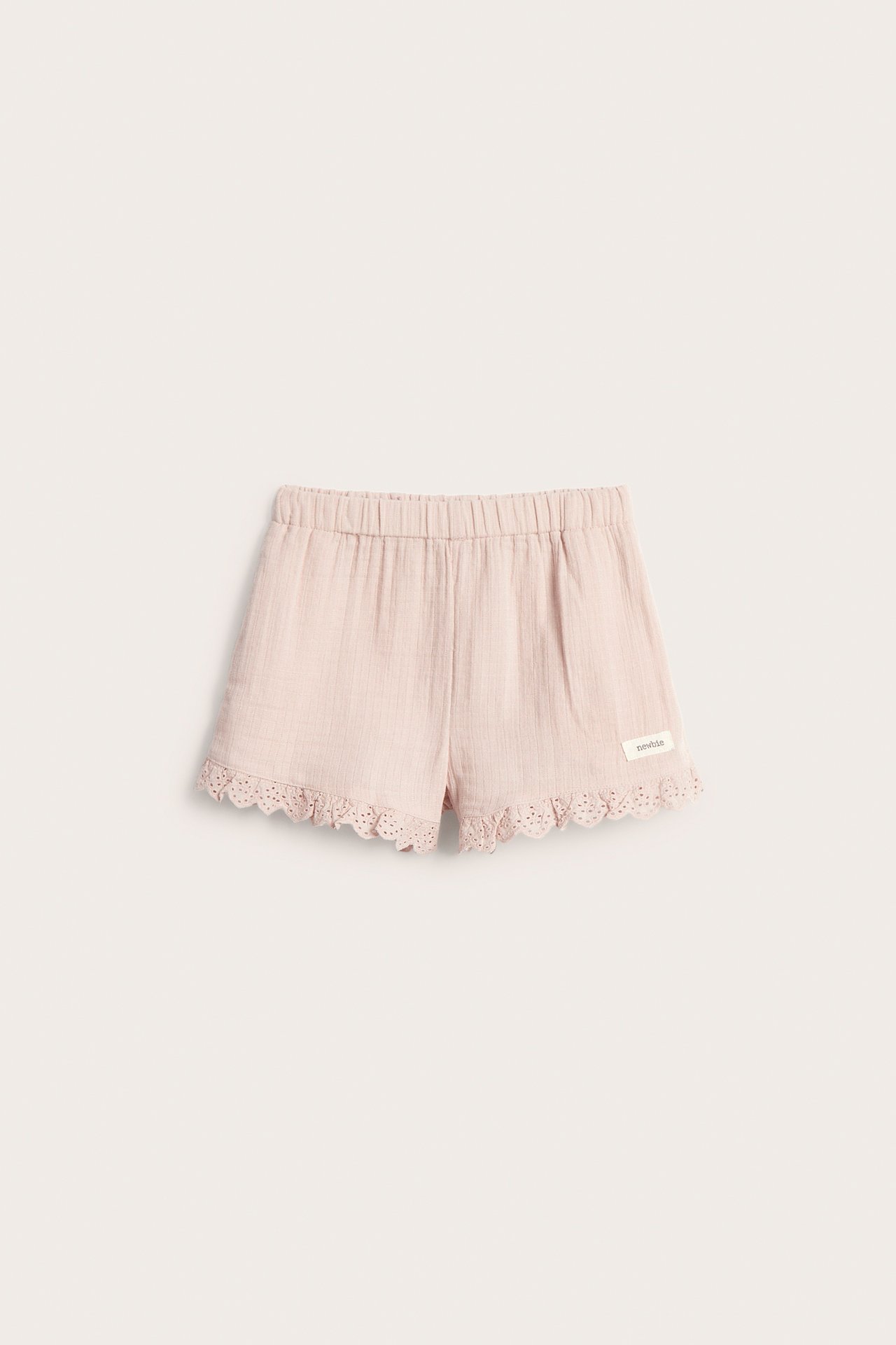 Front view of kid's light pink woven cotton shorts with elastic waist and lace trim.