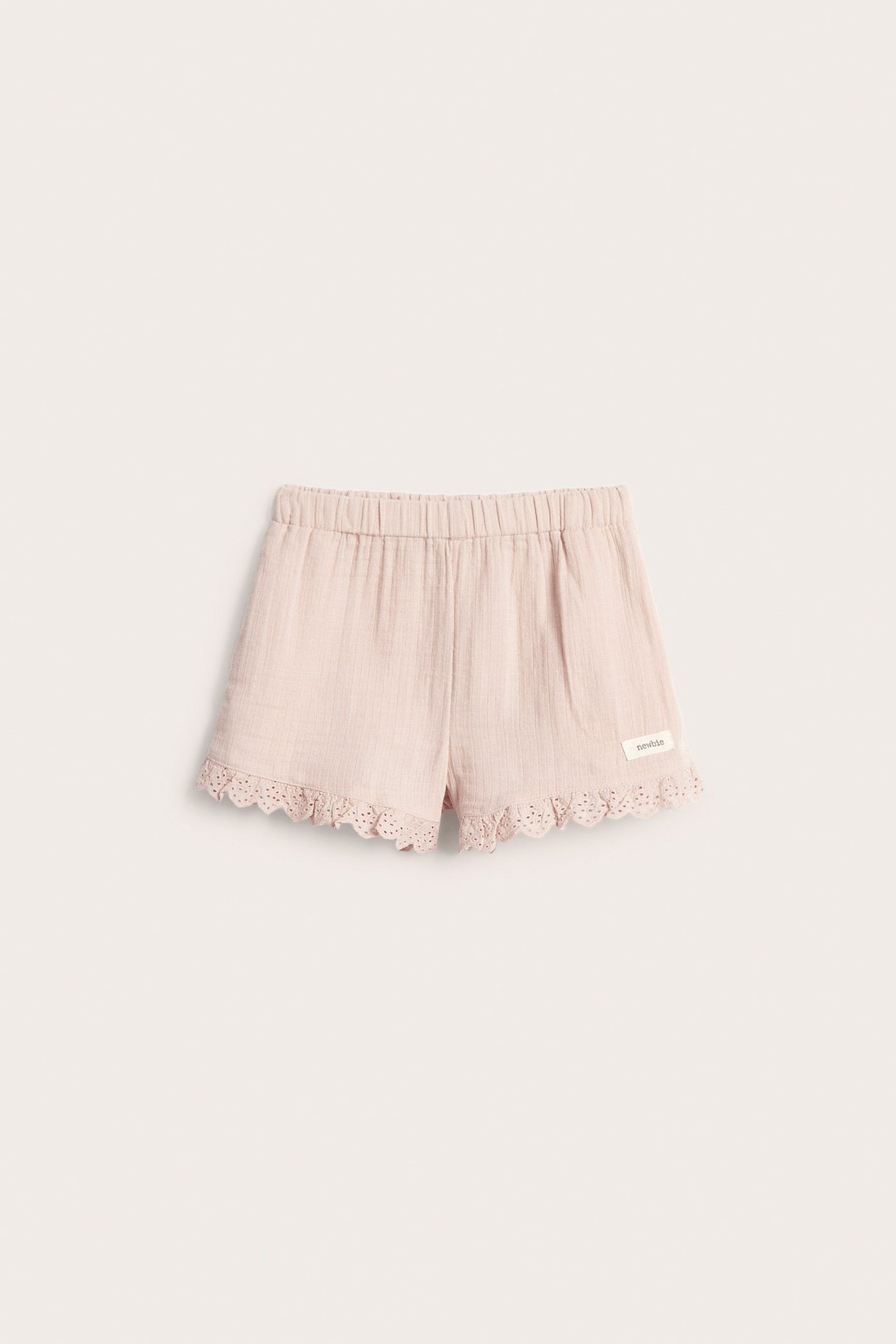 Front view of kid's light pink woven cotton shorts with elastic waist and lace trim.