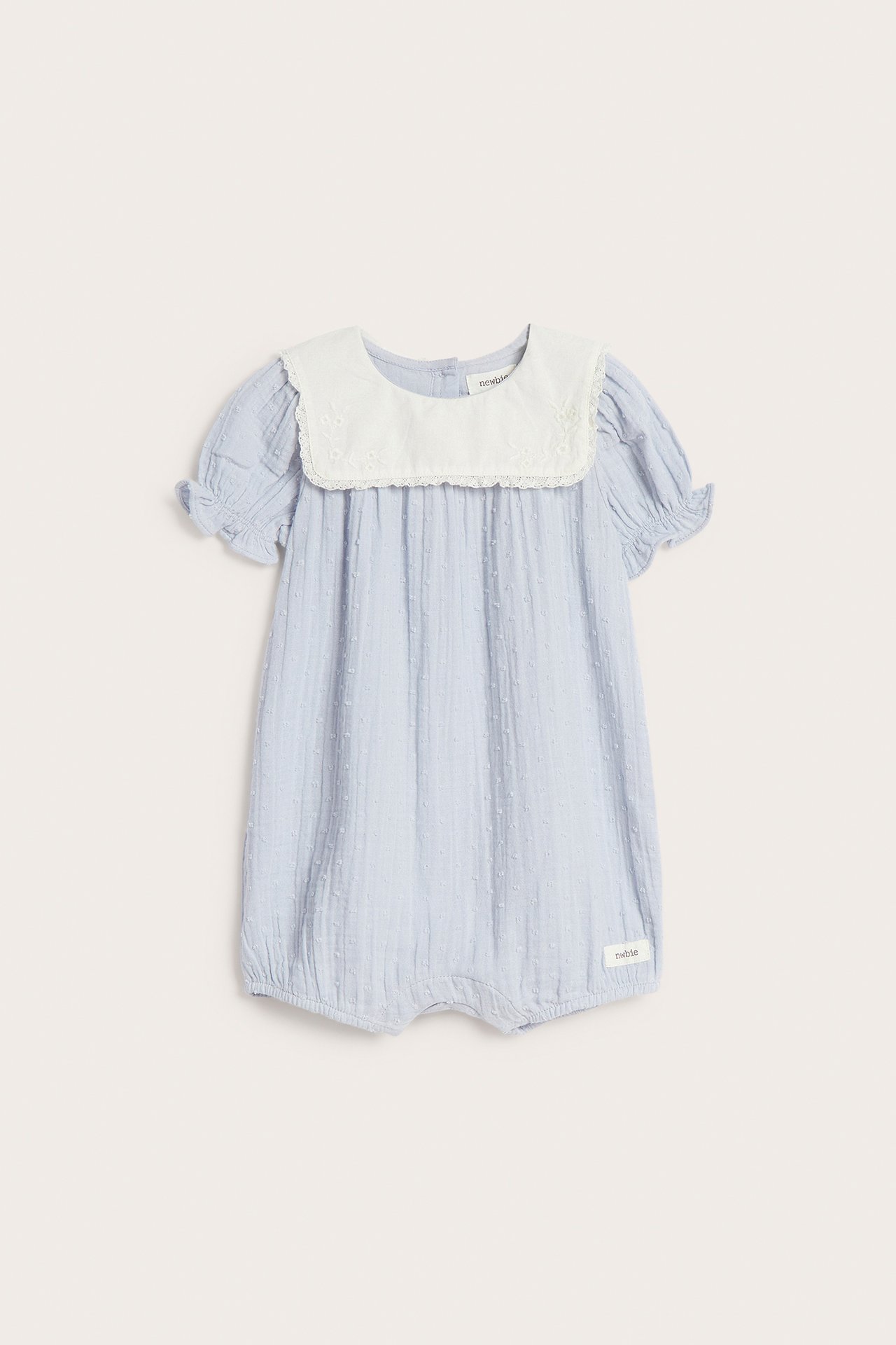 Front view of a baby's light blue dotted cotton playsuit with a white lace-edged sailor collar.