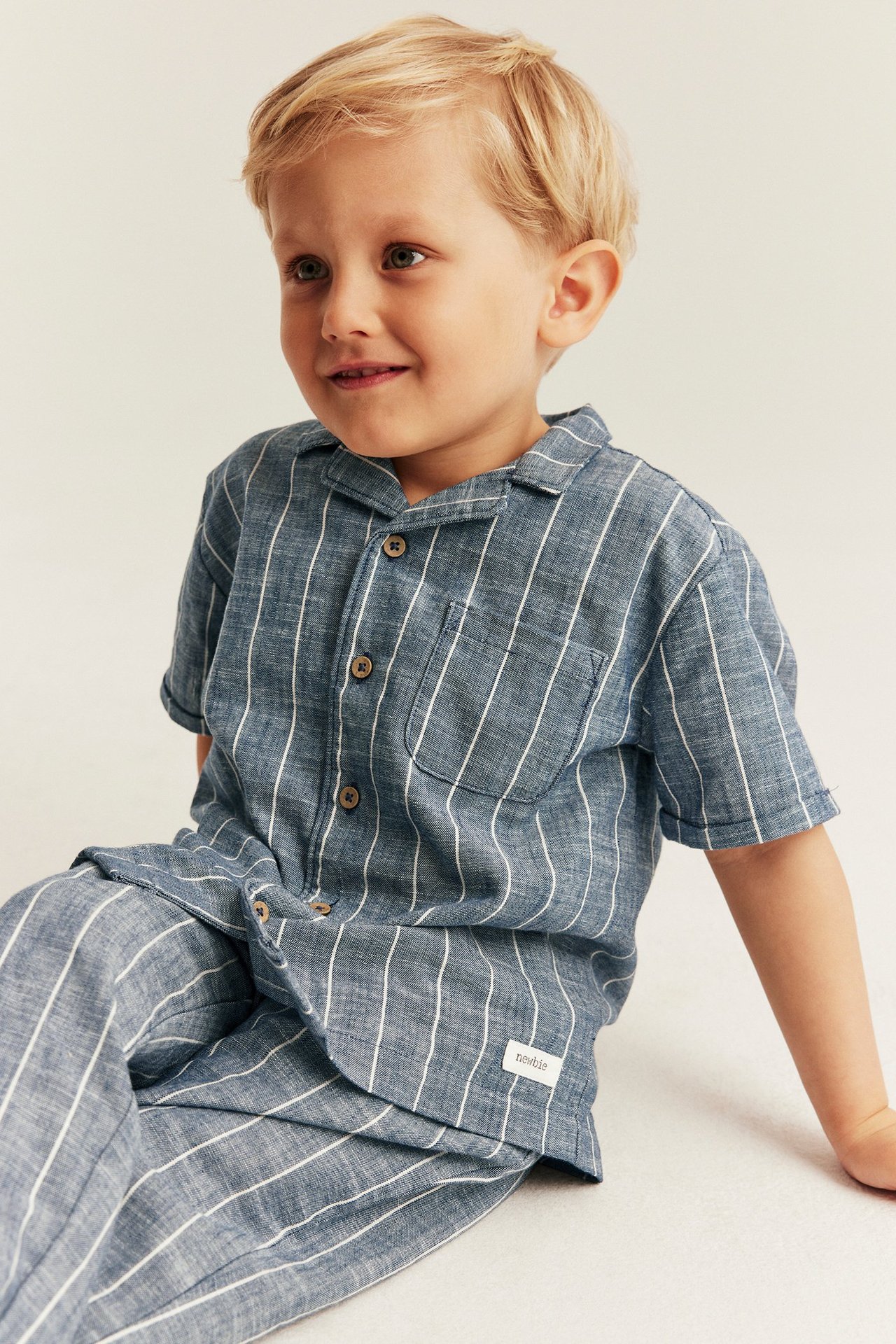 Front view: A kid wears a blue striped cotton shirt with collar, short sleeves, and matching pants.
