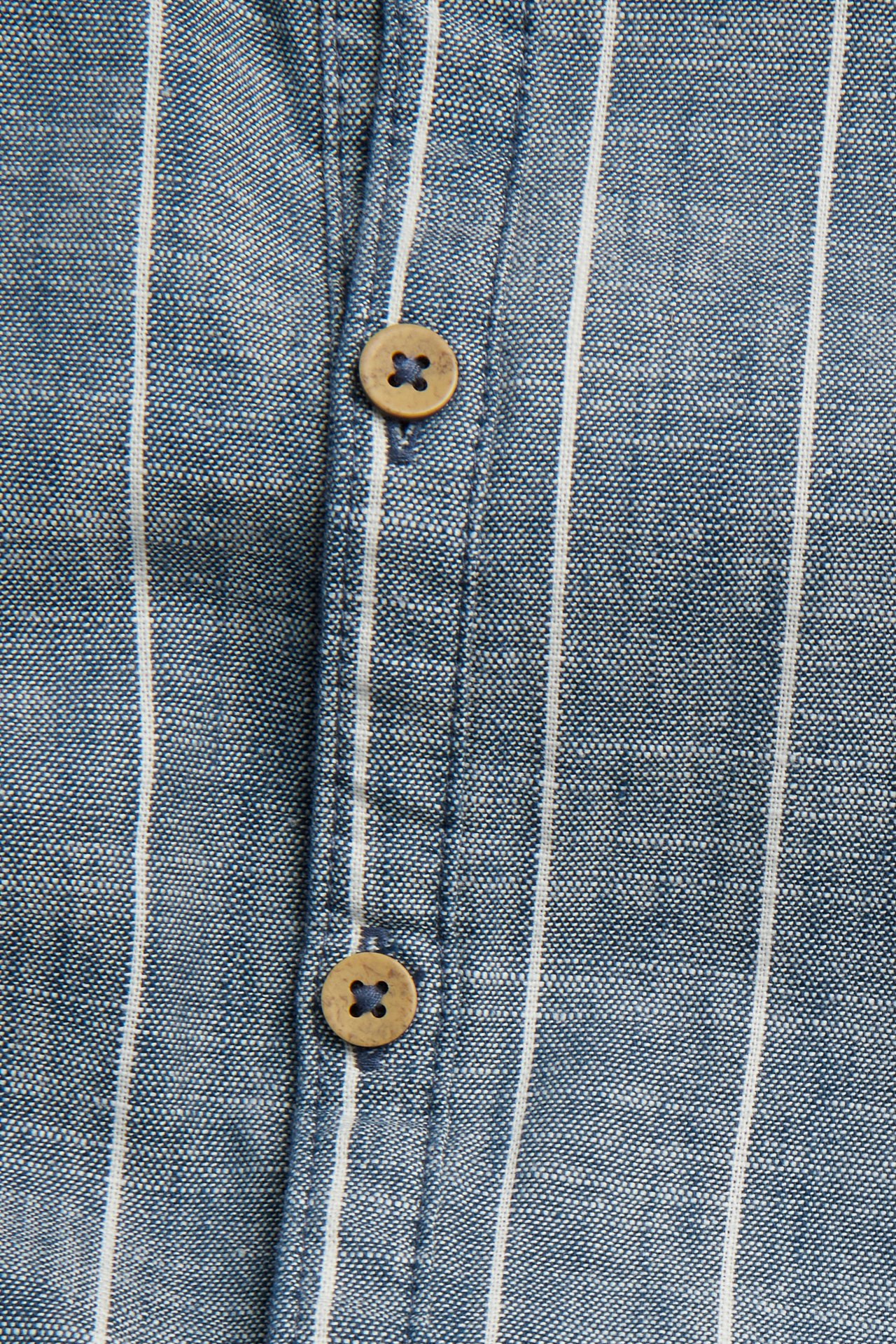 Close-up of a blue and white striped woven cotton romper with two brown wooden buttons.