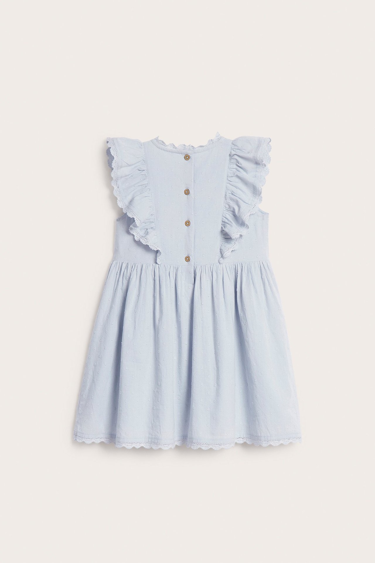 Back view of a kid's light blue woven cotton dress with ruffled shoulders, dot texture, lace trim, and back buttons.