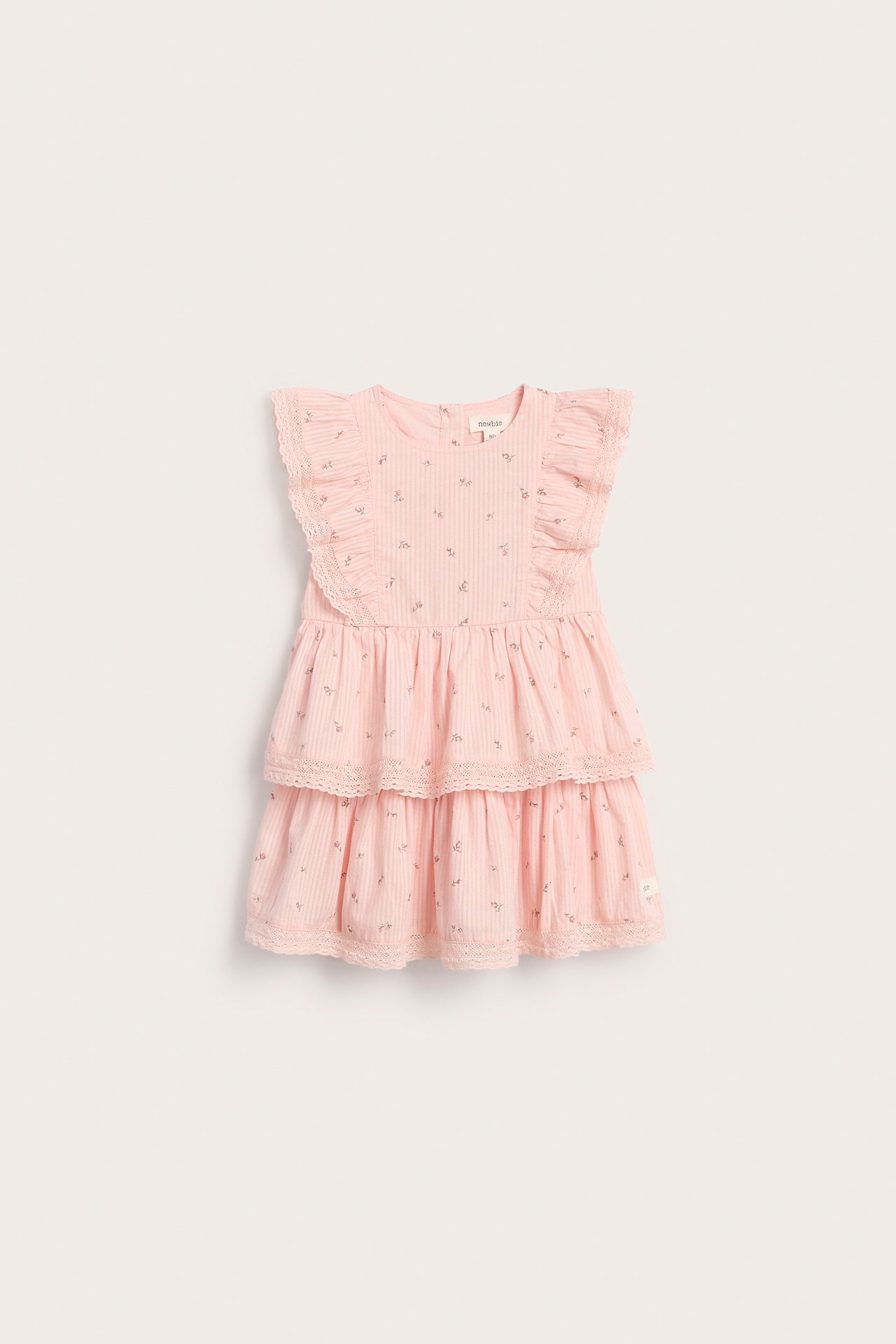 Front view of a kid's light pink floral tiered dress with ruffled cap sleeves and lace trim.
