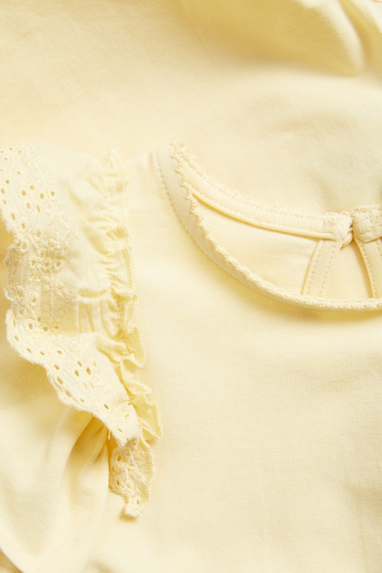 Close-up of a baby's light yellow short-sleeved bodysuit with ruffled lace sleeves and a picot stitch neckline.