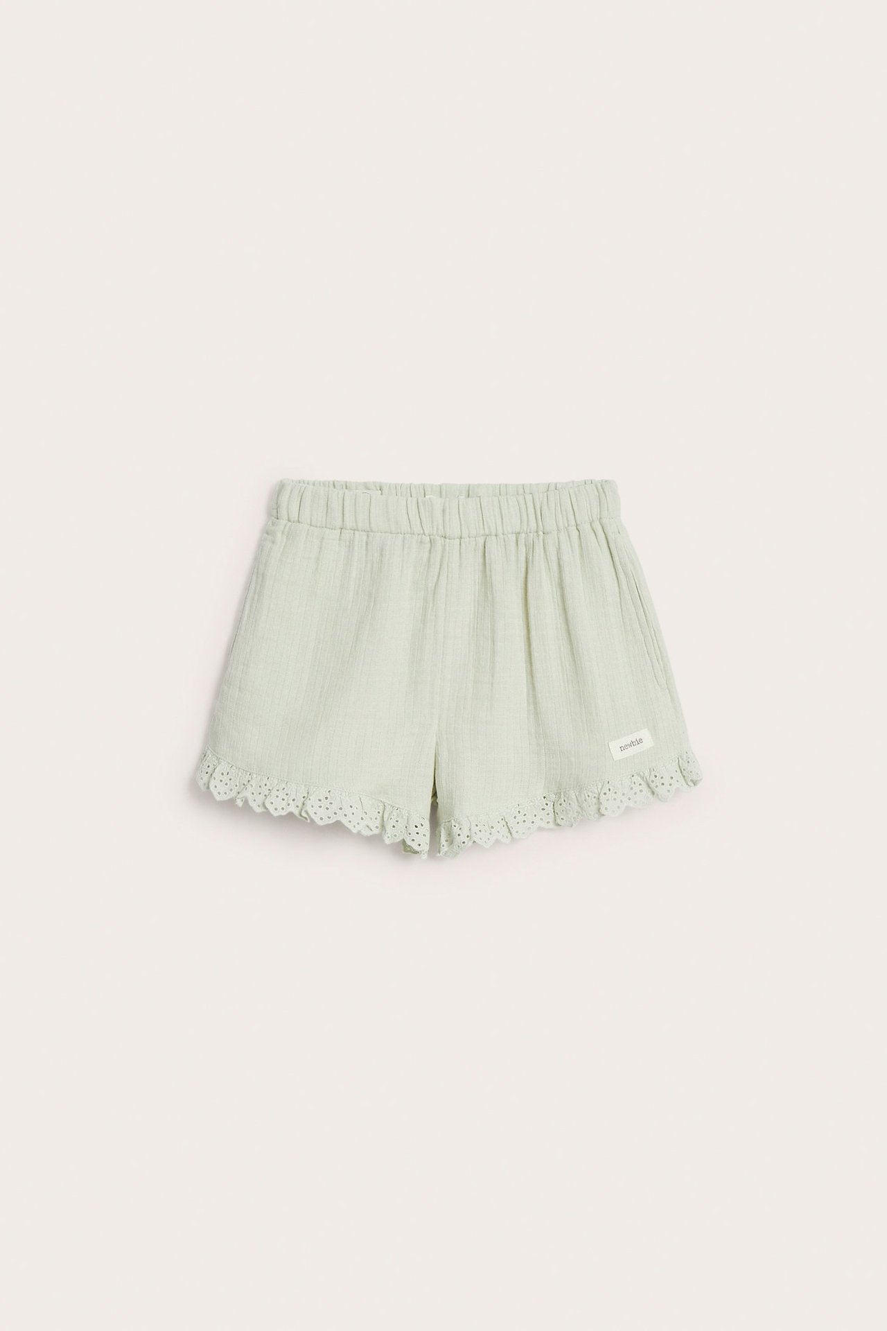 Vorderansicht von hellgrünen gewebten Baumwollshorts mit elastischem Bund und Spitzenvolant am Beinabschluss.