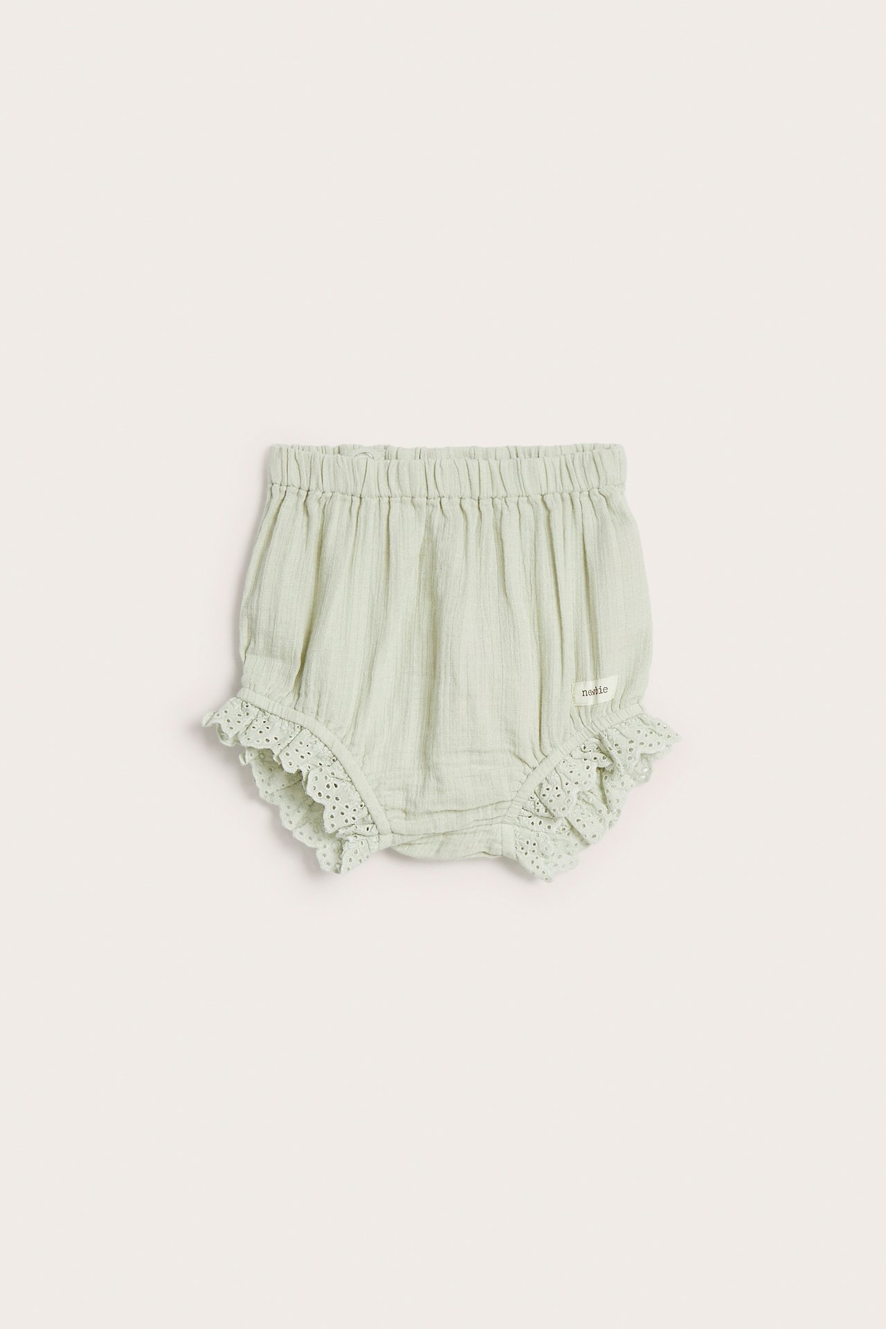 Front view of light green woven cotton baby shorts with elastic waist and lace ruffles.