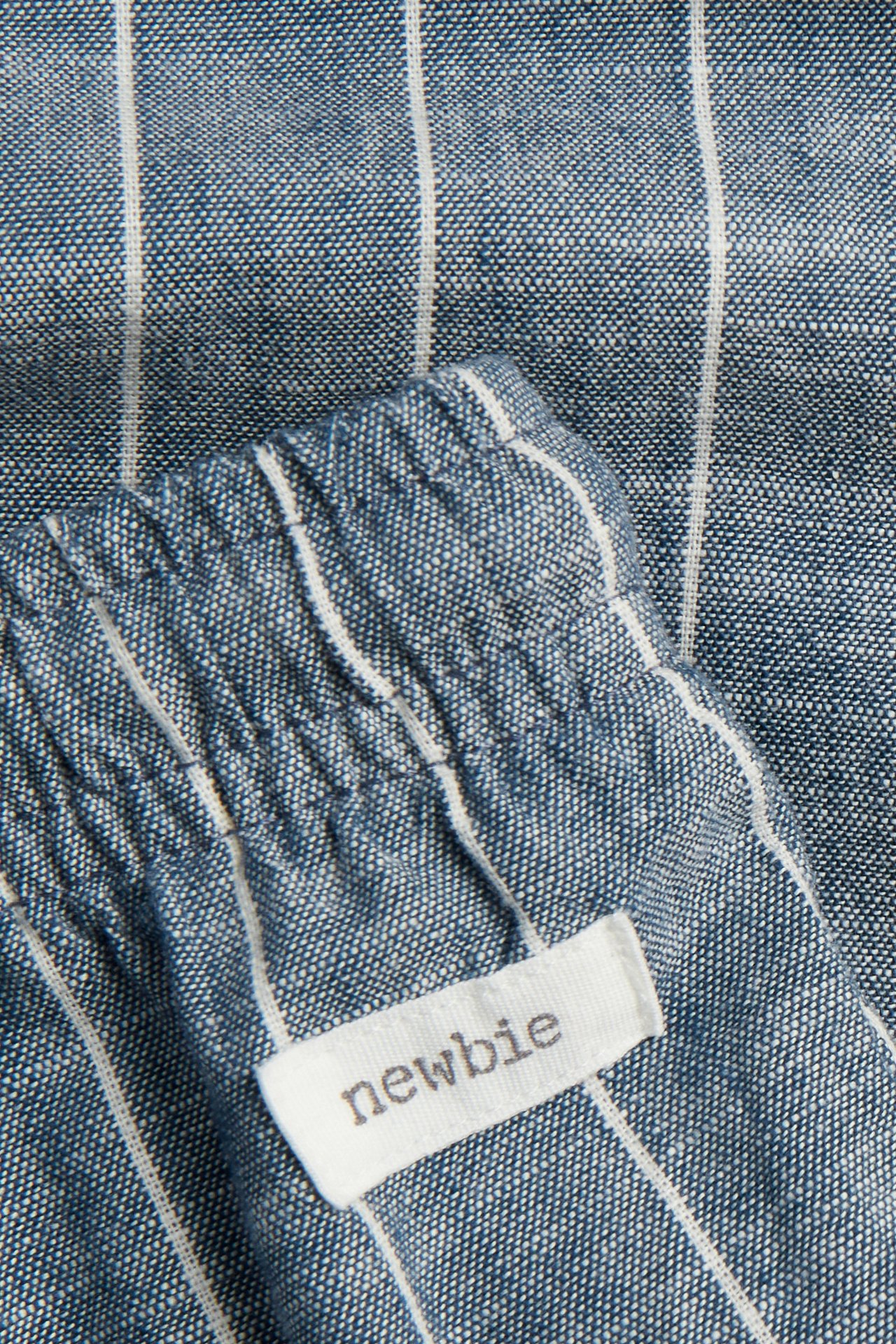 Nahaufnahme blauer und weiß gestreifter Baumwollhose mit Gummizugbund und einem 'Newbie'-Etikett.
