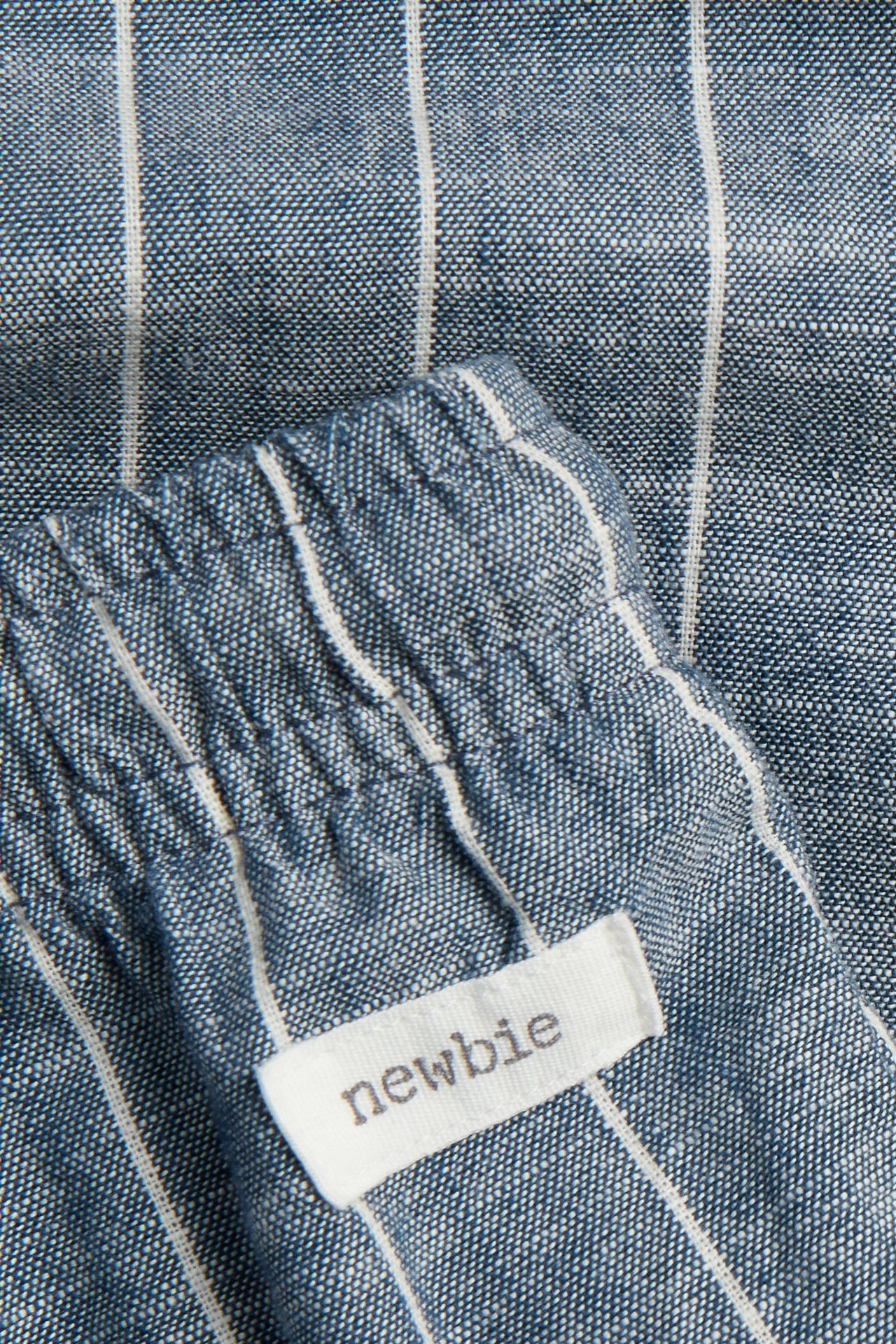 Nahaufnahme blauer und weiß gestreifter Baumwollhose mit Gummizugbund und einem 'Newbie'-Etikett.