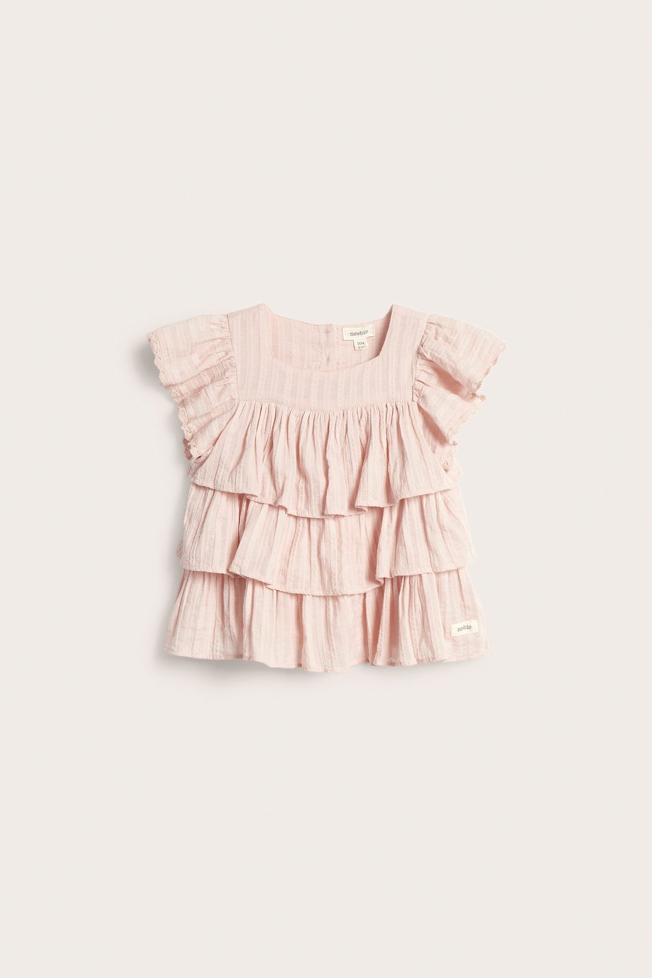 Front view: Light pink woven cotton baby blouse with square neck, ruffles, and lace sleeves.