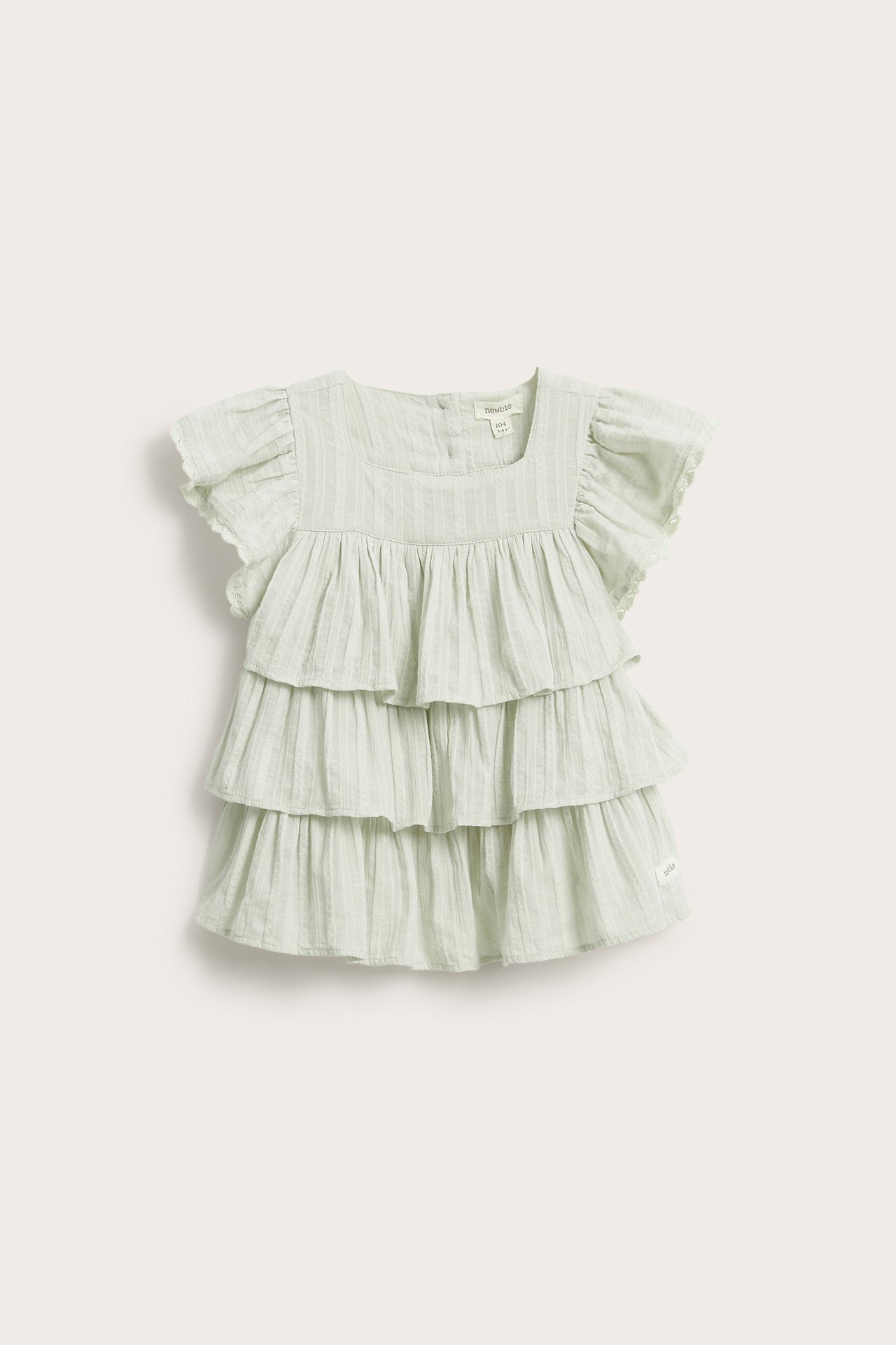 Front view: Baby's light green woven ruffled blouse with square neck and lace-trimmed sleeves.