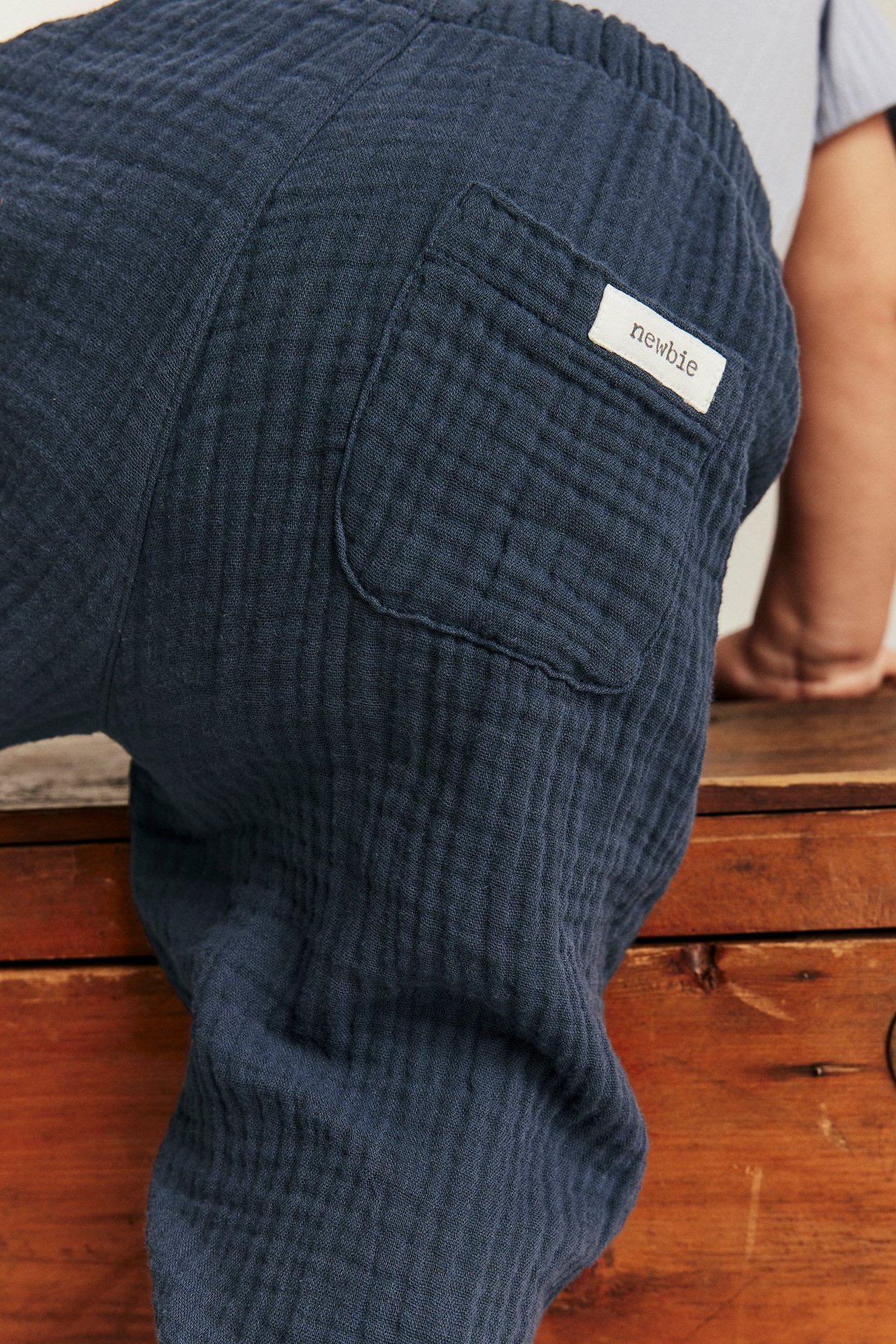 Nahaufnahme Rückansicht einer Babyhose aus dunkelblauem Baumwollmusselin mit einer aufgesetzten Gesäßtasche.