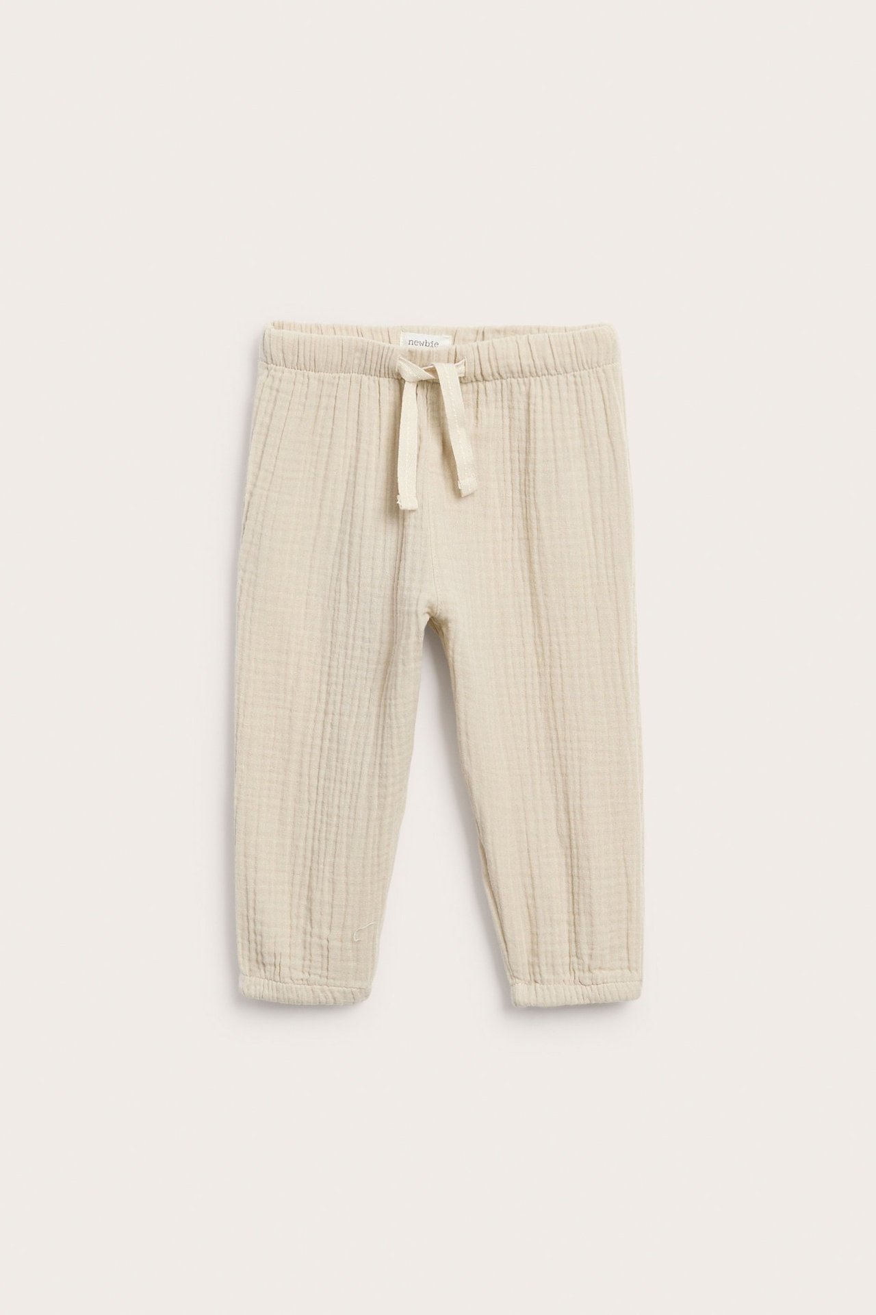 Vorderansicht: Off-white gewebte Musselin-Babyhose mit Gummizugbund und Kordelzug.