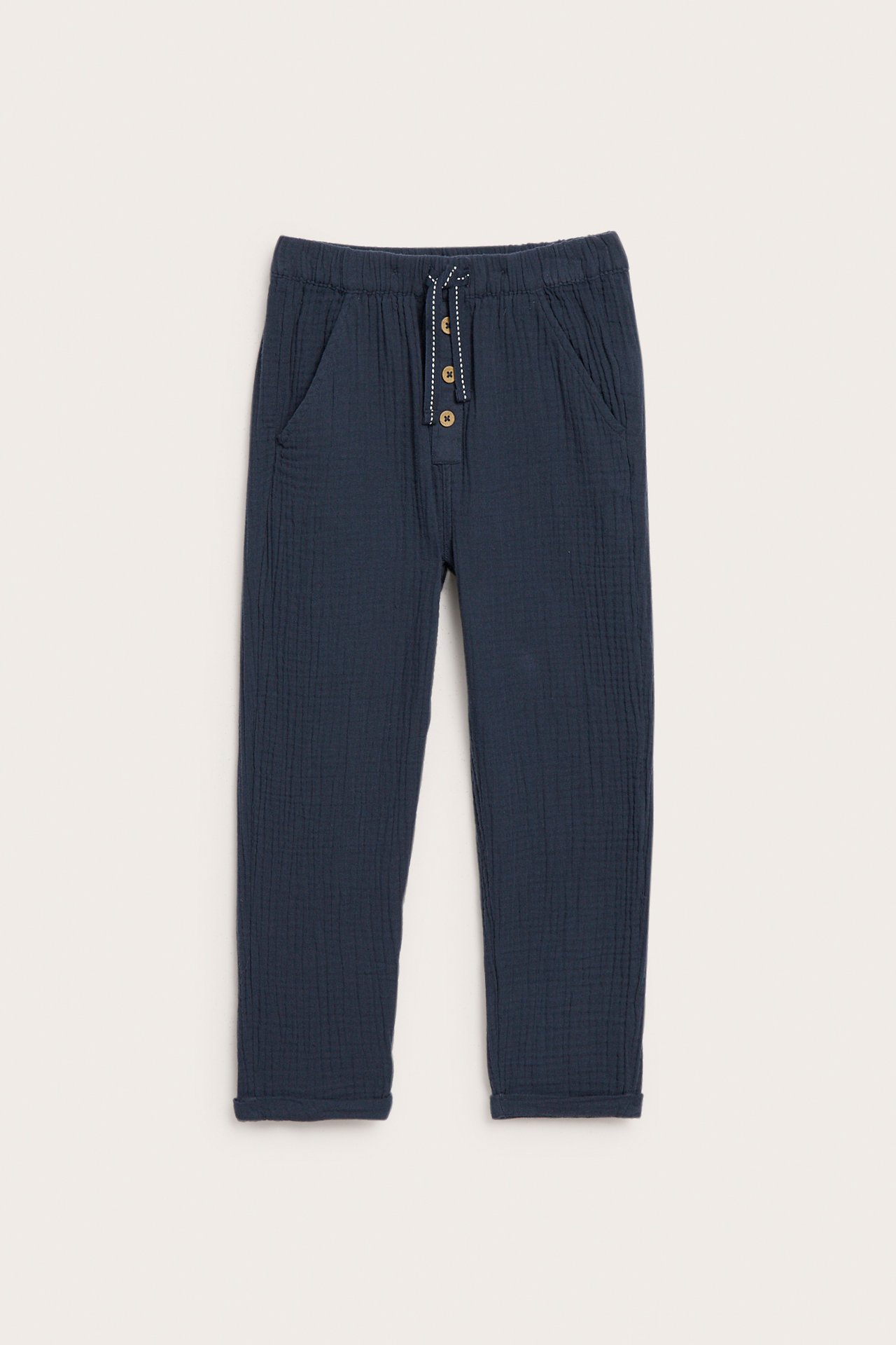 Vorderansicht: Dunkelblaue Baumwollmusselin-Kinderhose mit Gummibund, Zugband, Knöpfen und hochgekrempelten Beinenden.