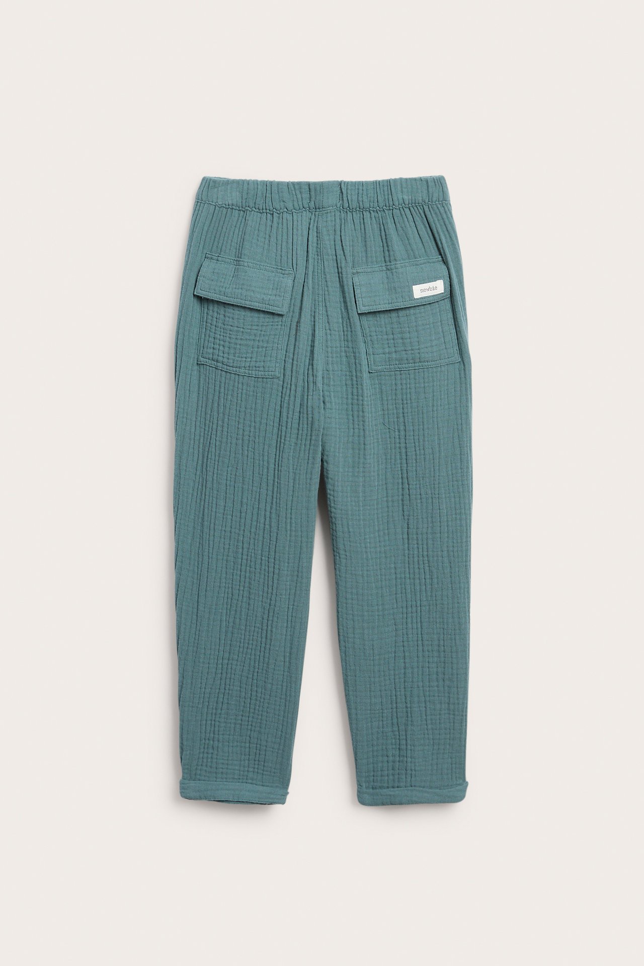Rückansicht: Dunkel-türkise Musselin-Baumwollhose mit elastischem Bund, zwei Pattentaschen hinten und umgekrempelten Bündchen.