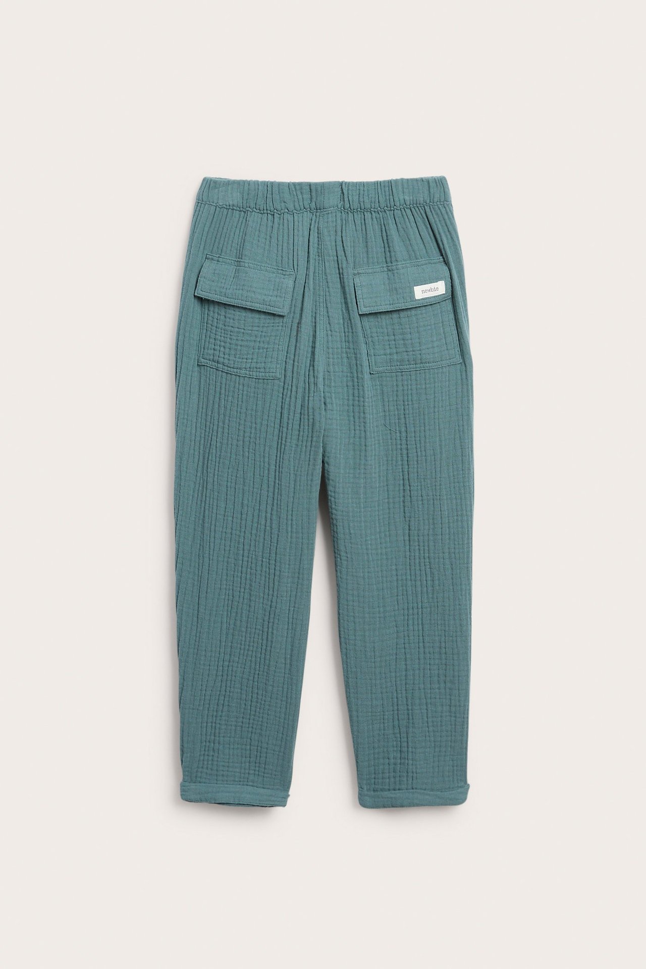 Rückansicht: Dunkel-türkise Musselin-Baumwollhose mit elastischem Bund, zwei Pattentaschen hinten und umgekrempelten Bündchen.