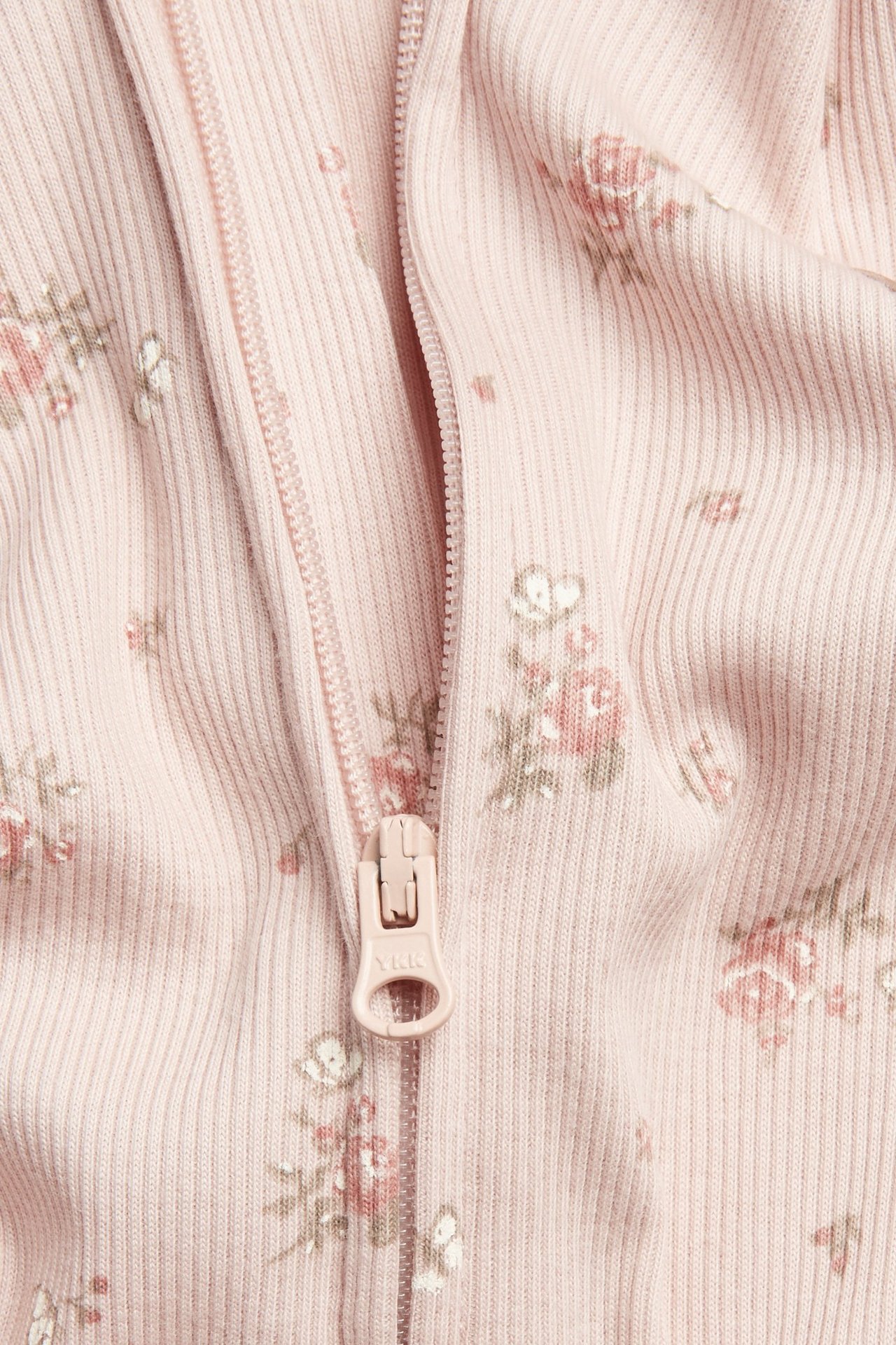 Nahaufnahme: rosa gerippter Baby-Baumwollpyjamas mit Blumen-Schmetterlingsprint und Reißverschluss.