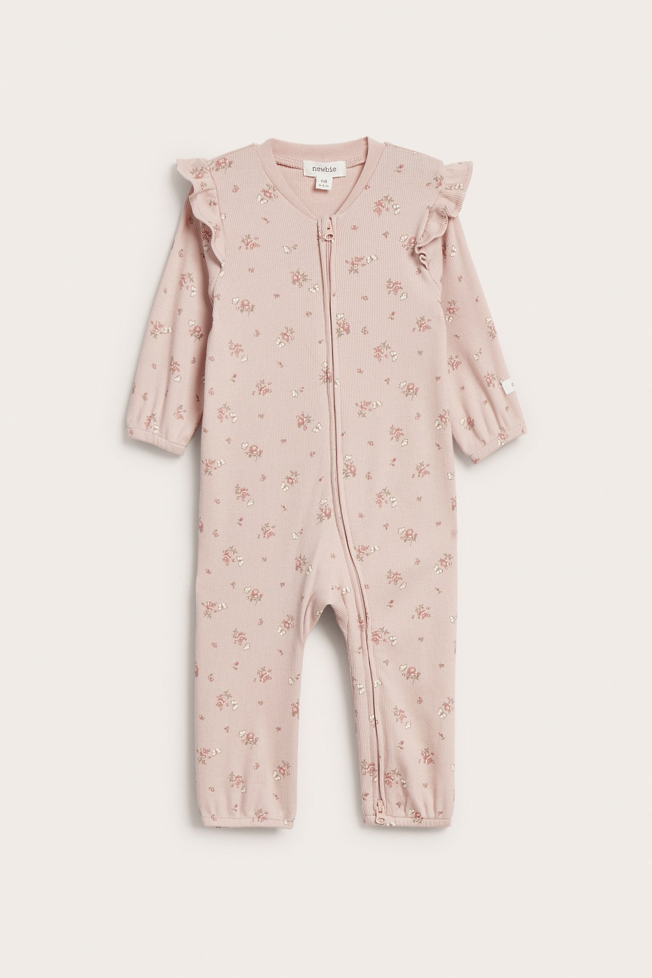 Vorderansicht: Baby-Pyjama aus rosa Rippstoff mit Blumenmuster, Schulterrüschen und Reißverschluss.