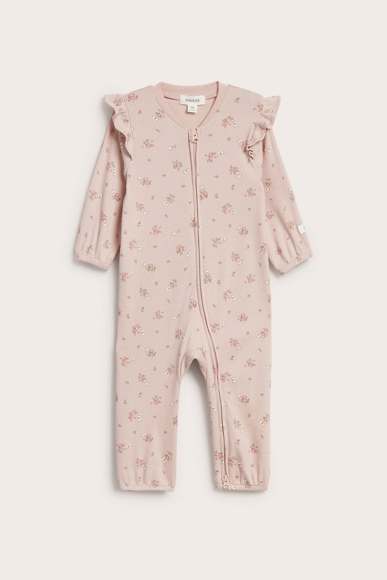Vorderansicht: Baby-Pyjama aus rosa Rippstoff mit Blumenmuster, Schulterrüschen und Reißverschluss.