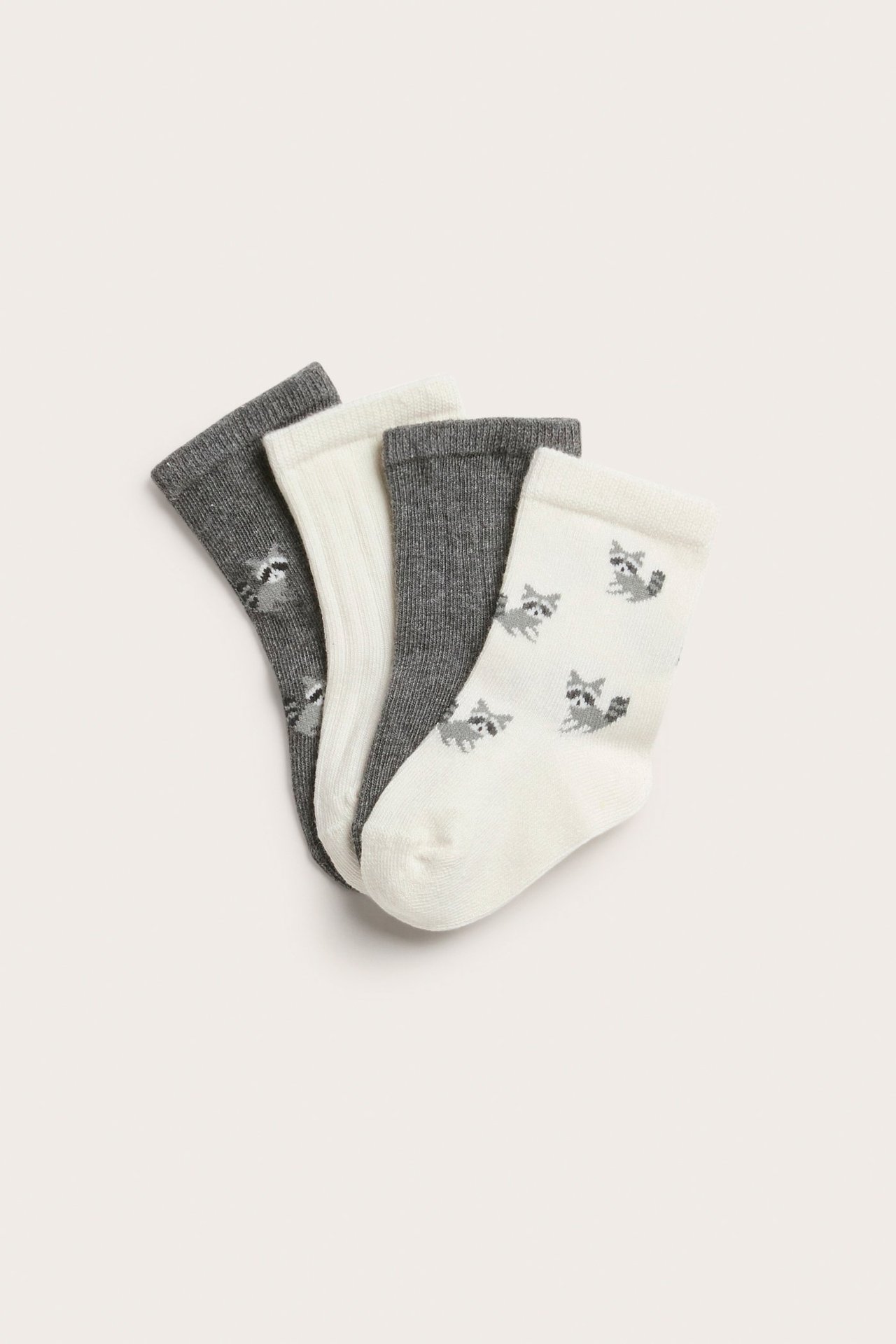 Vier Paar Babysocken: zwei graue, ein geripptes cremefarbenes, ein cremefarbenes mit Waschbär-Muster.