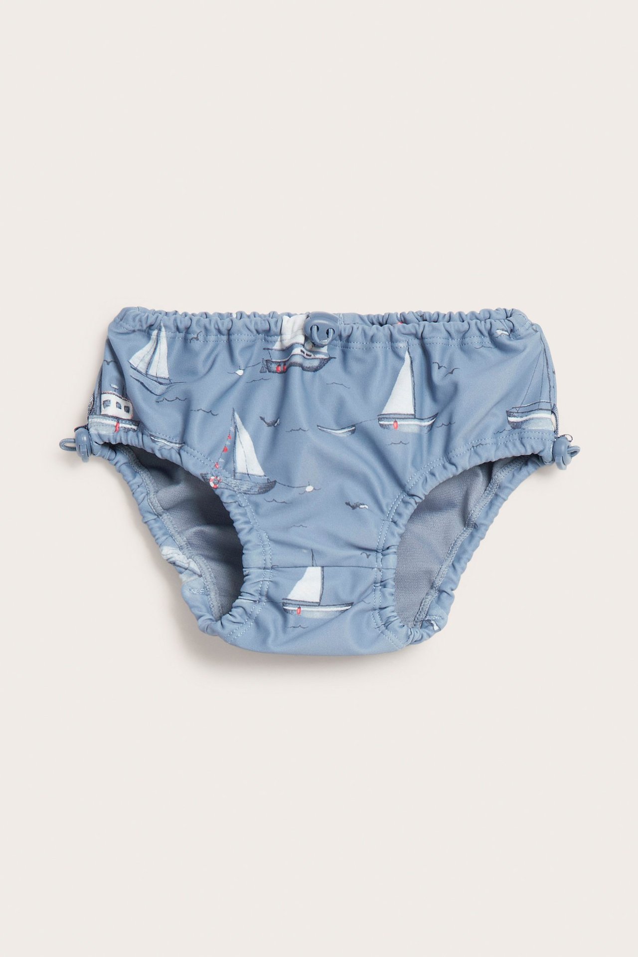 Vorderansicht blauer Baby-Badehose mit Booten, elastischem Bund und verstellbaren Beinabschlüssen.
