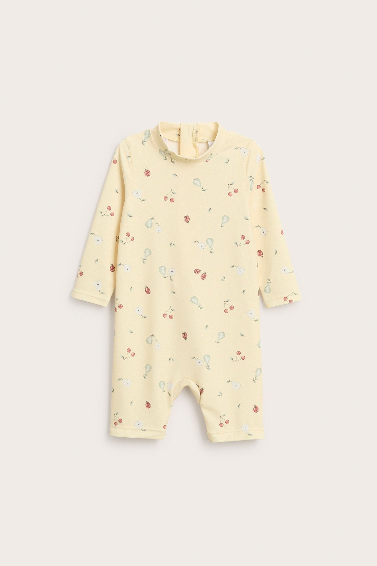 Front view: yellow UV romper with cherry, pear, and ladybug pattern, long sleeves, and back zipper.