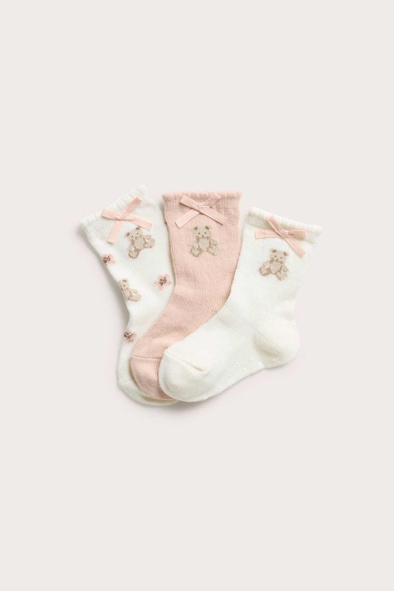 Aufsicht: Ein 3er-Pack cremeweißer und hellrosa Babysocken aus Baumwollmix mit gestickten Teddybären und rosa Schleifen.