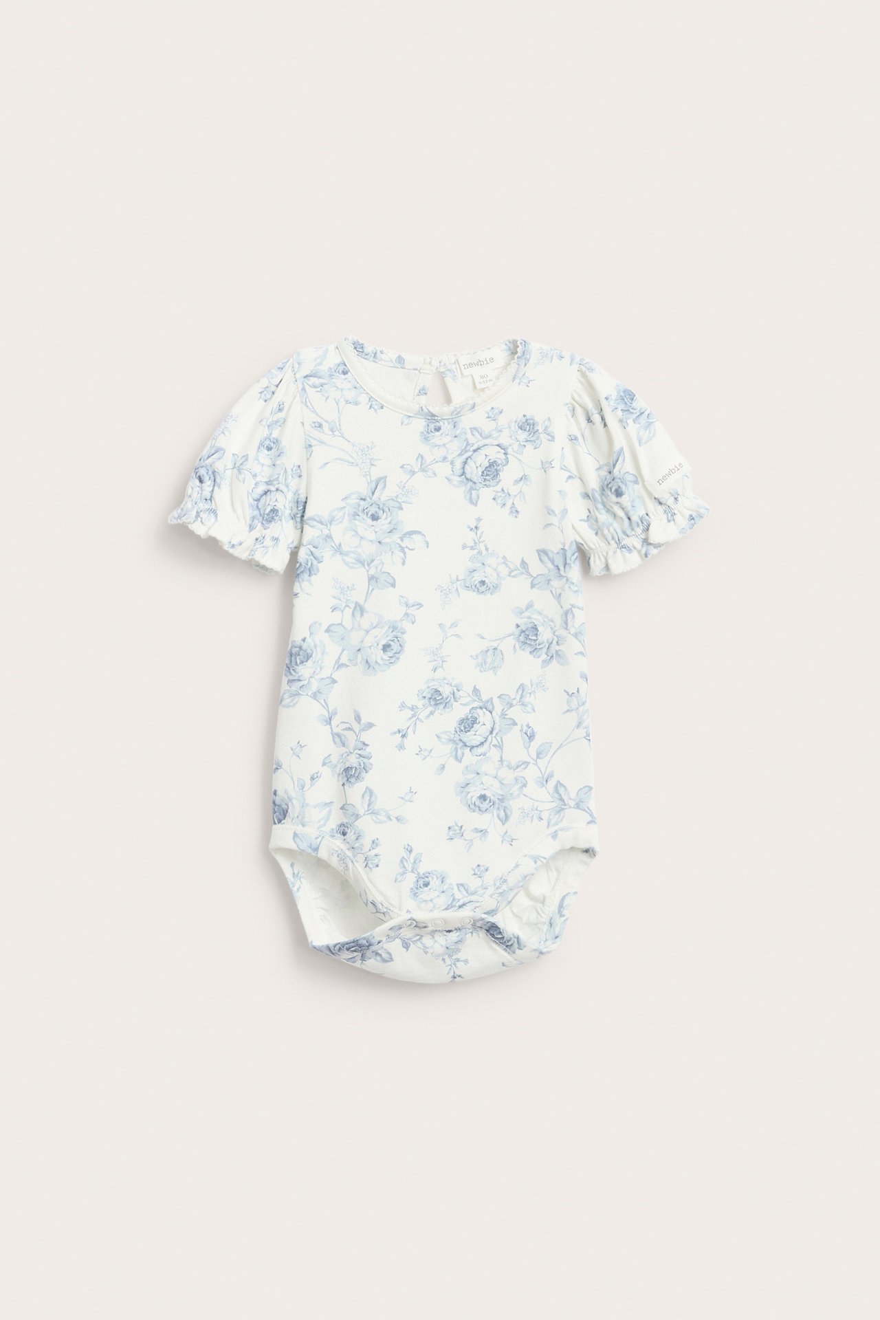 Front view: Off-white baby bodysuit with blue floral print, short puff sleeves, elasticated cuffs, and picot trim.