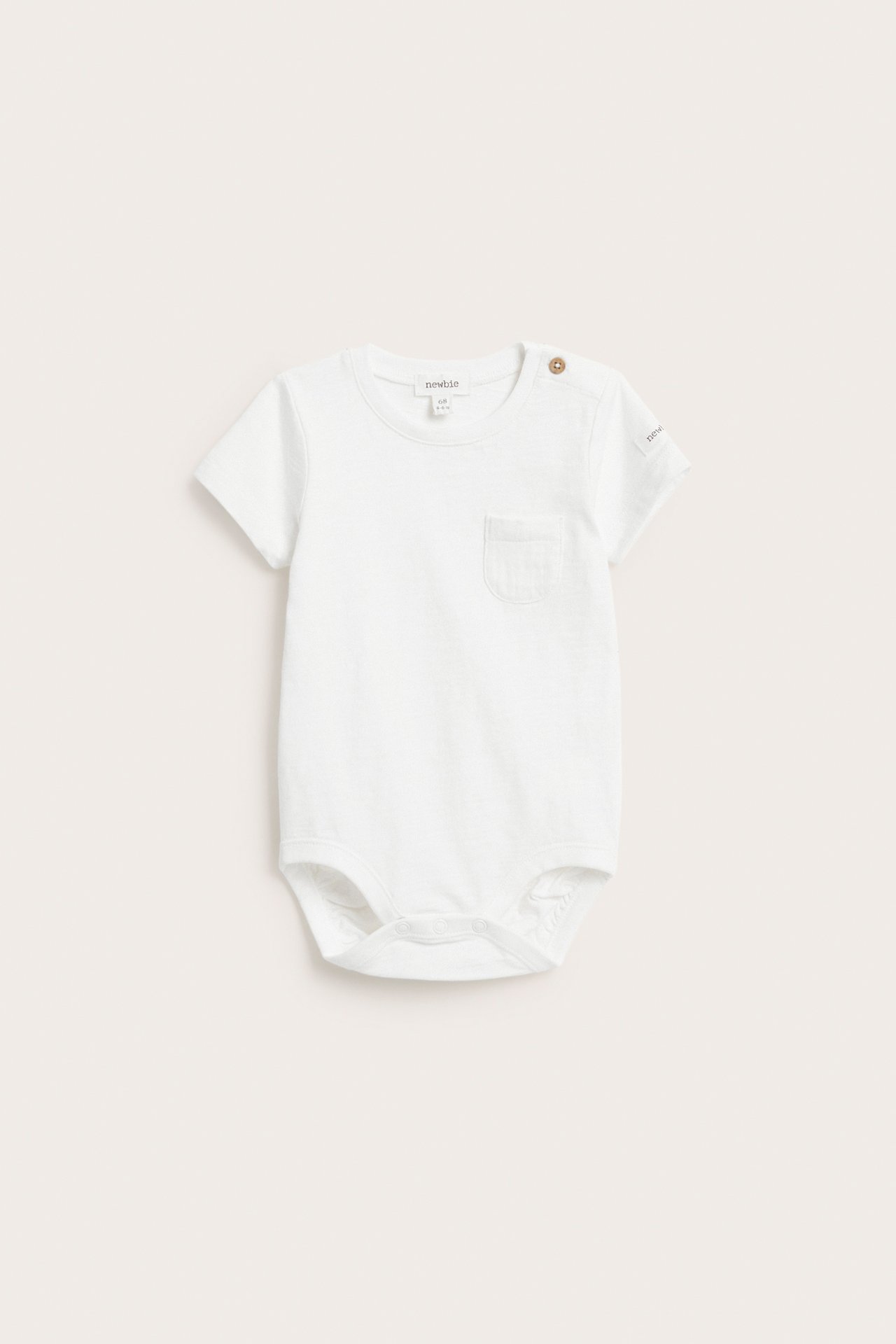 Front view of an off-white baby short-sleeved cotton bodysuit with shoulder buttons and a chest pocket.