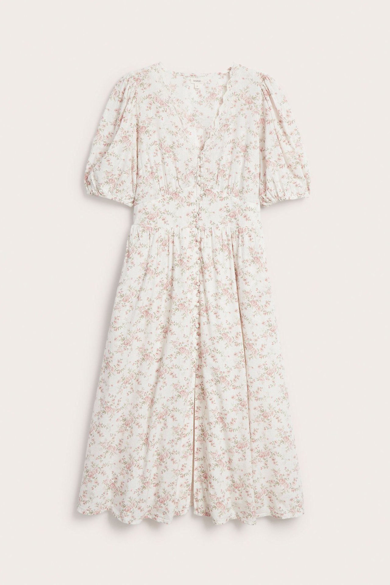 Front view of an off-white cotton dress with pink floral pattern, V-neck, button-front, and short puff sleeves.