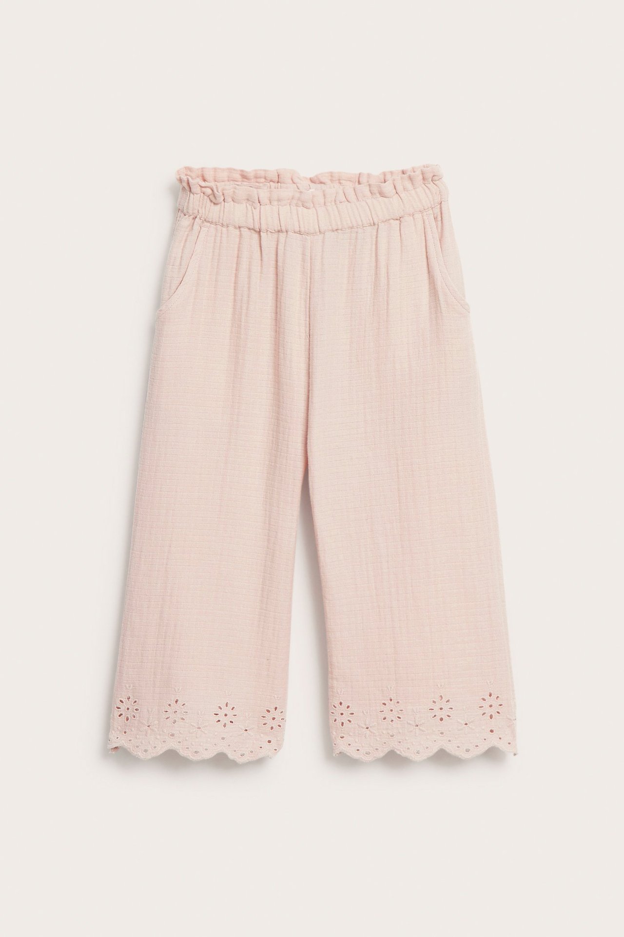 Front view of light pink woven cotton trousers with an elasticated waist, side pockets, and scalloped embroidery at the hem.