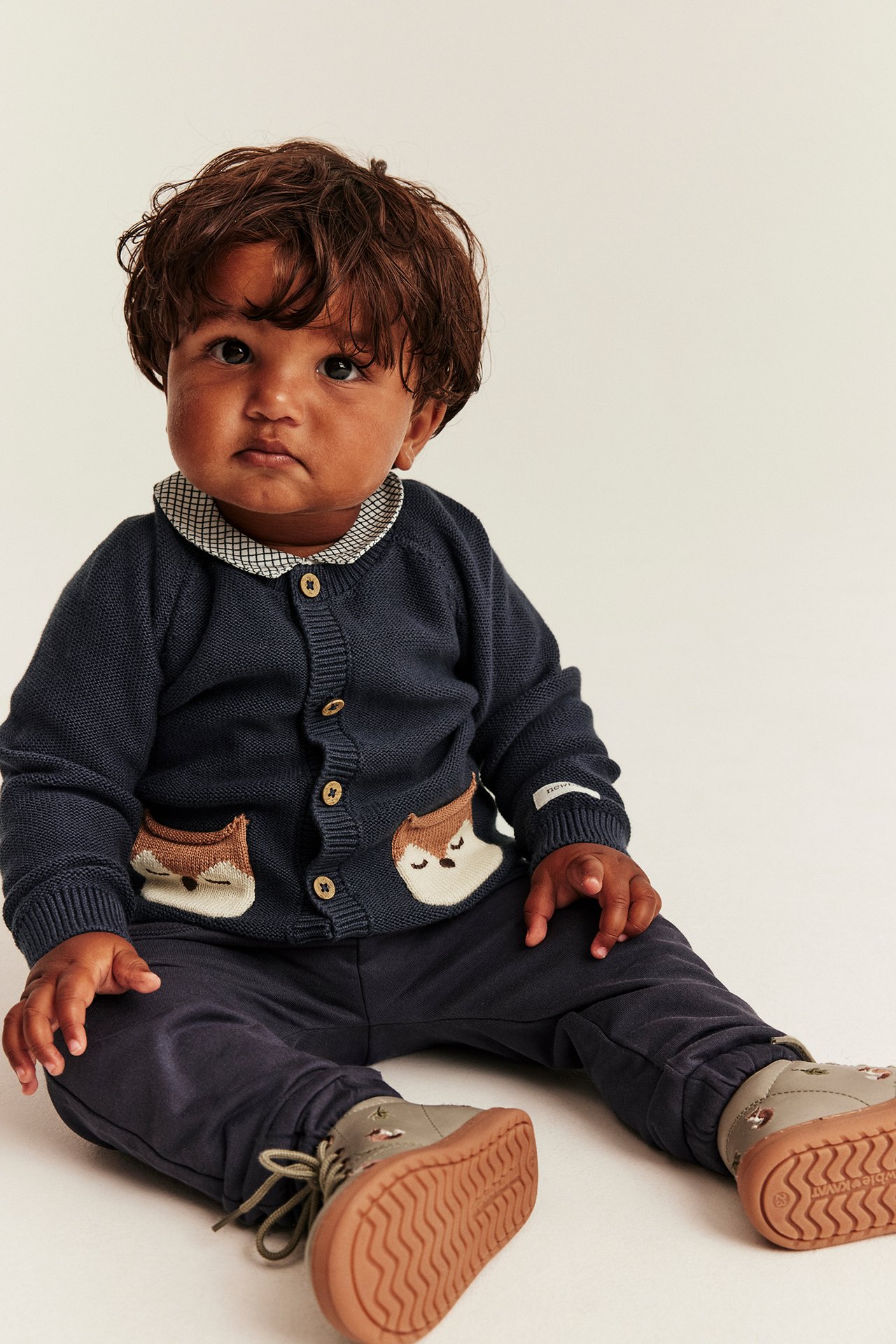 Baby's navy knit cardigan with fox appliques, navy pants, and gray shoes, front view.