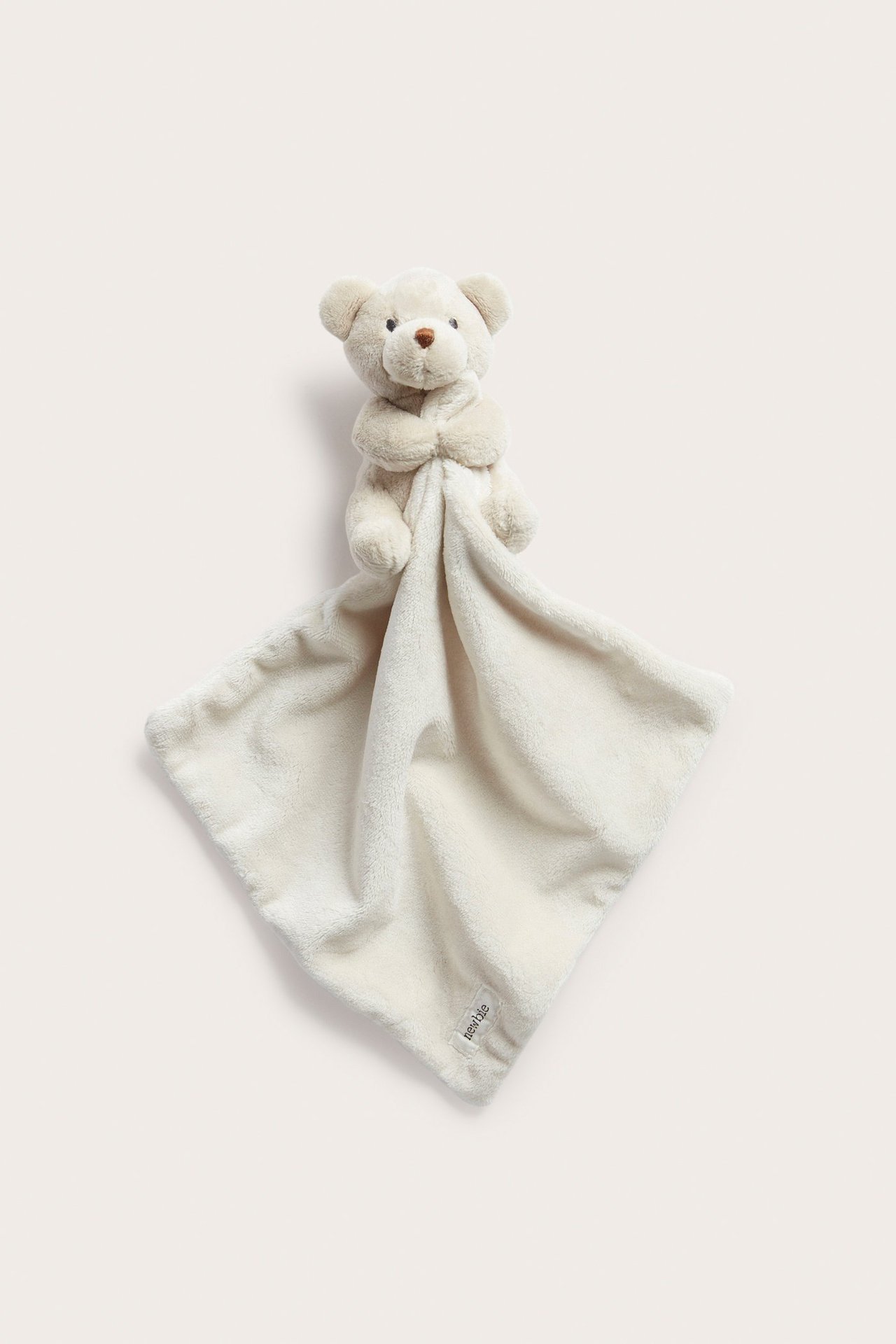 Vorderansicht einer hellbeigen, weichen Polyester-Schmusedecke mit angenähtem Teddybärenkopf.