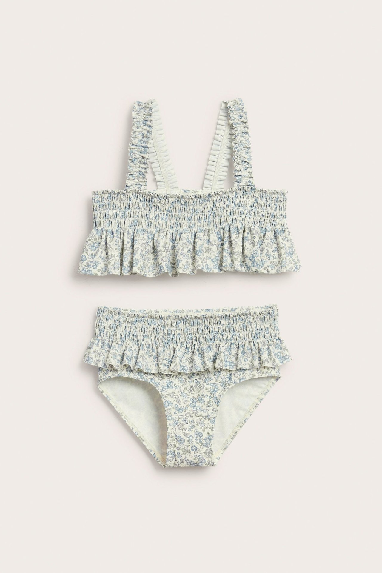 Vorderansicht: Kinder-Bikini mit gesmoktem Oberteil und Höschen in hellblau/grünem Blumenmuster, Rüschen an Trägern.