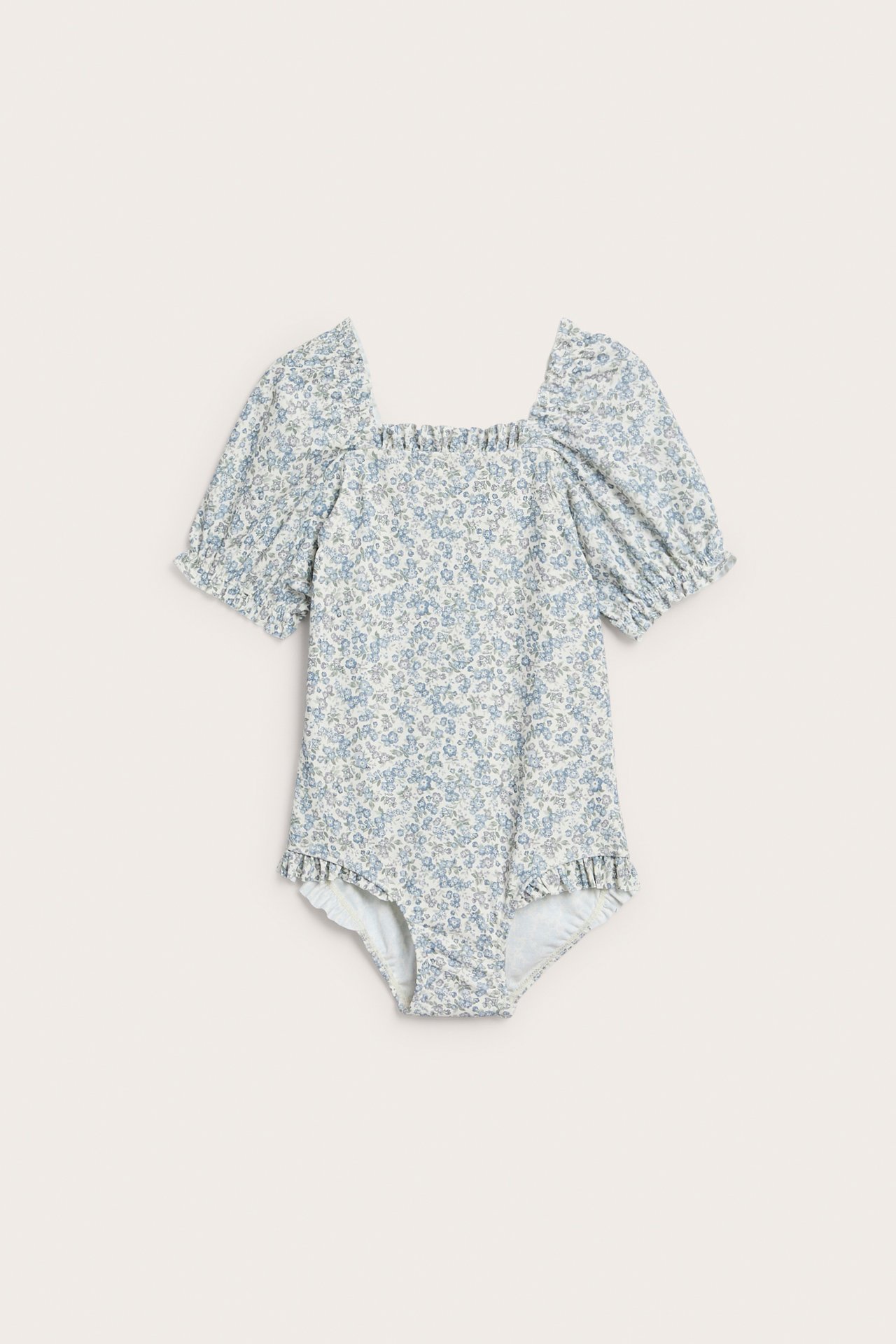 Front view of a baby's light blue floral swimsuit with puff sleeves and ruffled leg openings.