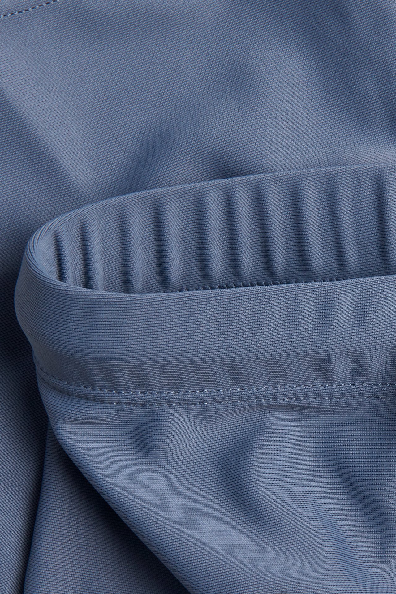 Nahaufnahme einfarbiger blauer dreiviertellanger UV-Badehosen mit geripptem Gummizugdetail.