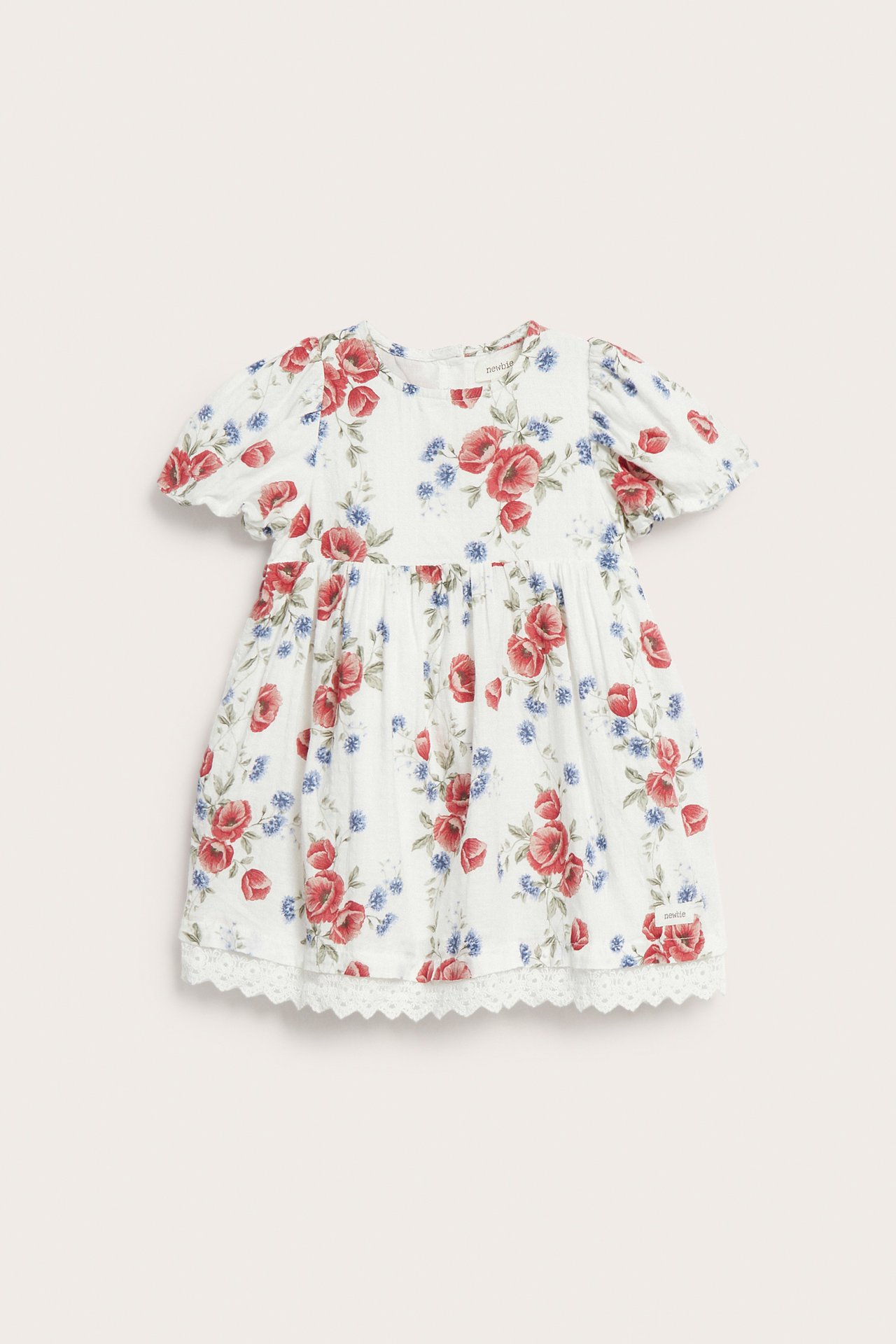 Vorderansicht: Cremeweißes Babykleid mit Puffärmeln, rot/blauem Blumenmuster und Spitzenbesatz.