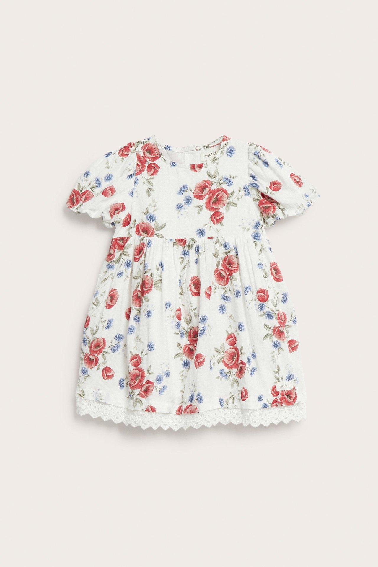 Vorderansicht: Cremeweißes Babykleid mit Puffärmeln, rot/blauem Blumenmuster und Spitzenbesatz.