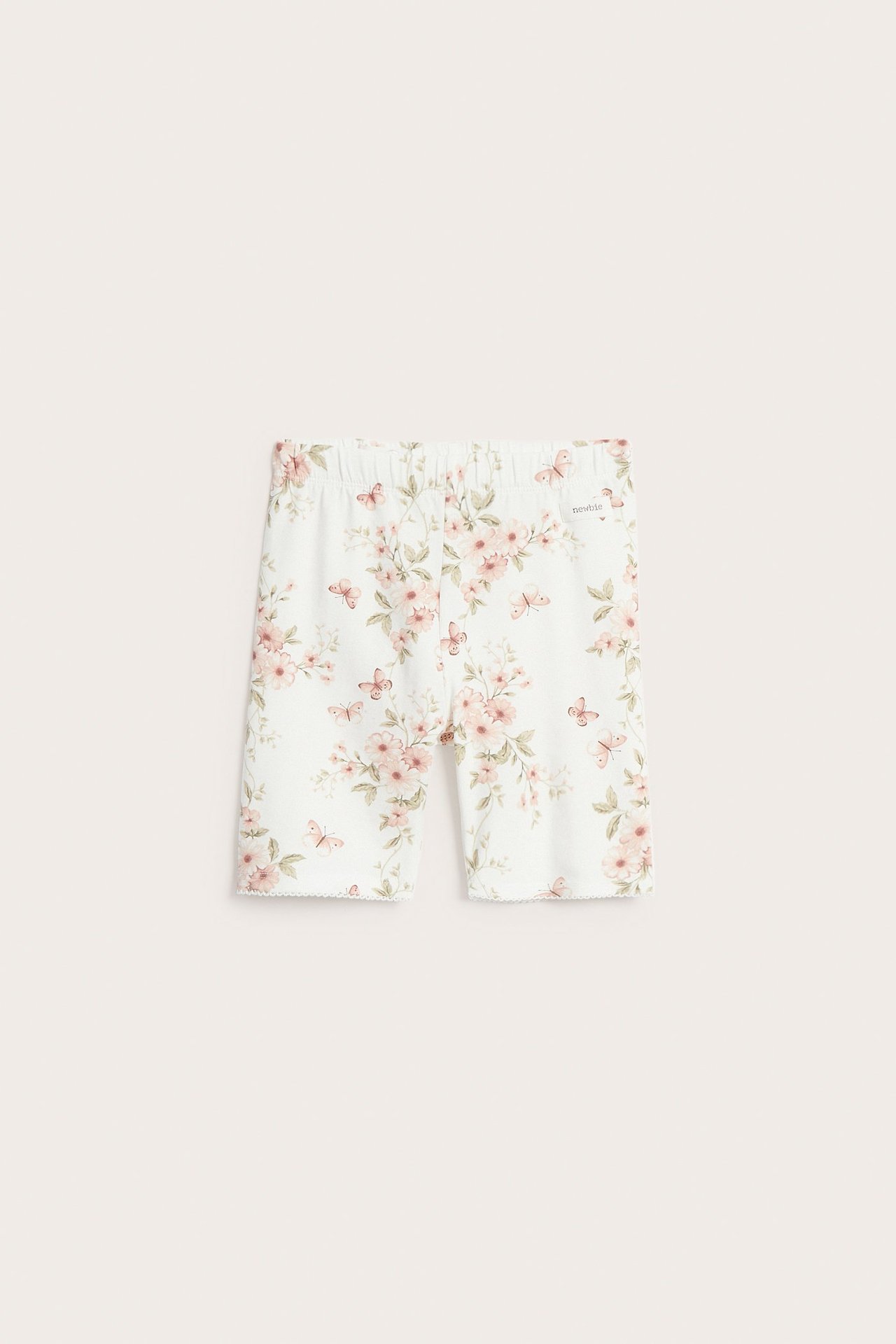 Vorderansicht von cremefarbenen Jersey-Radlerhosen mit Blumen- und Schmetterlingsmuster, Gummizug und Picot-Saum.