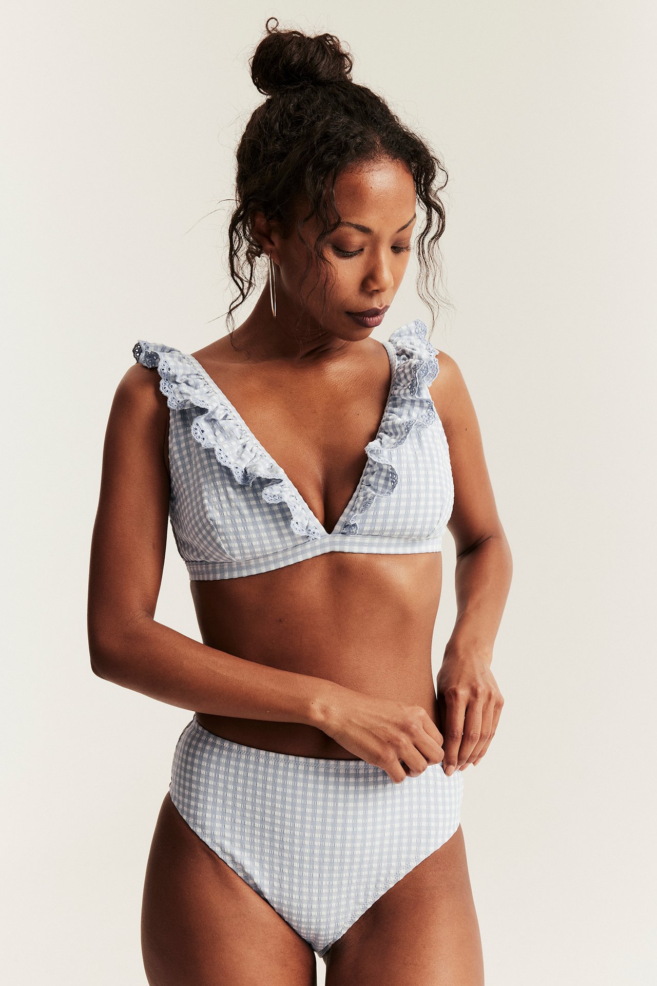 Front view: Woman in blue and white checkered high-waisted bikini bottom and matching ruffled top.