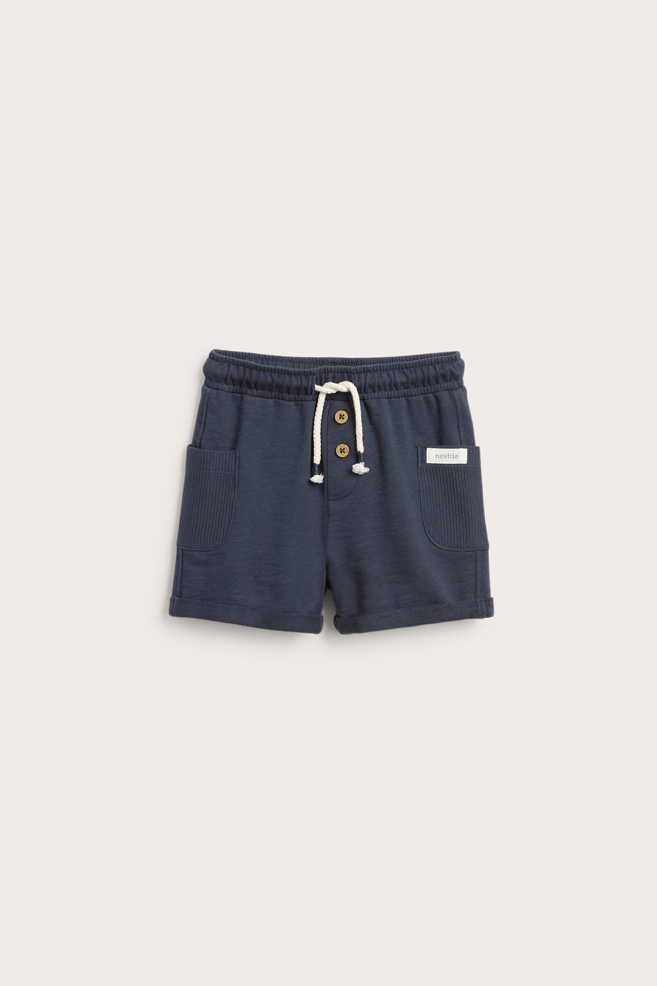 Front view of dark blue slub jersey baby shorts with an elastic waist, cream drawstring, and buttons.