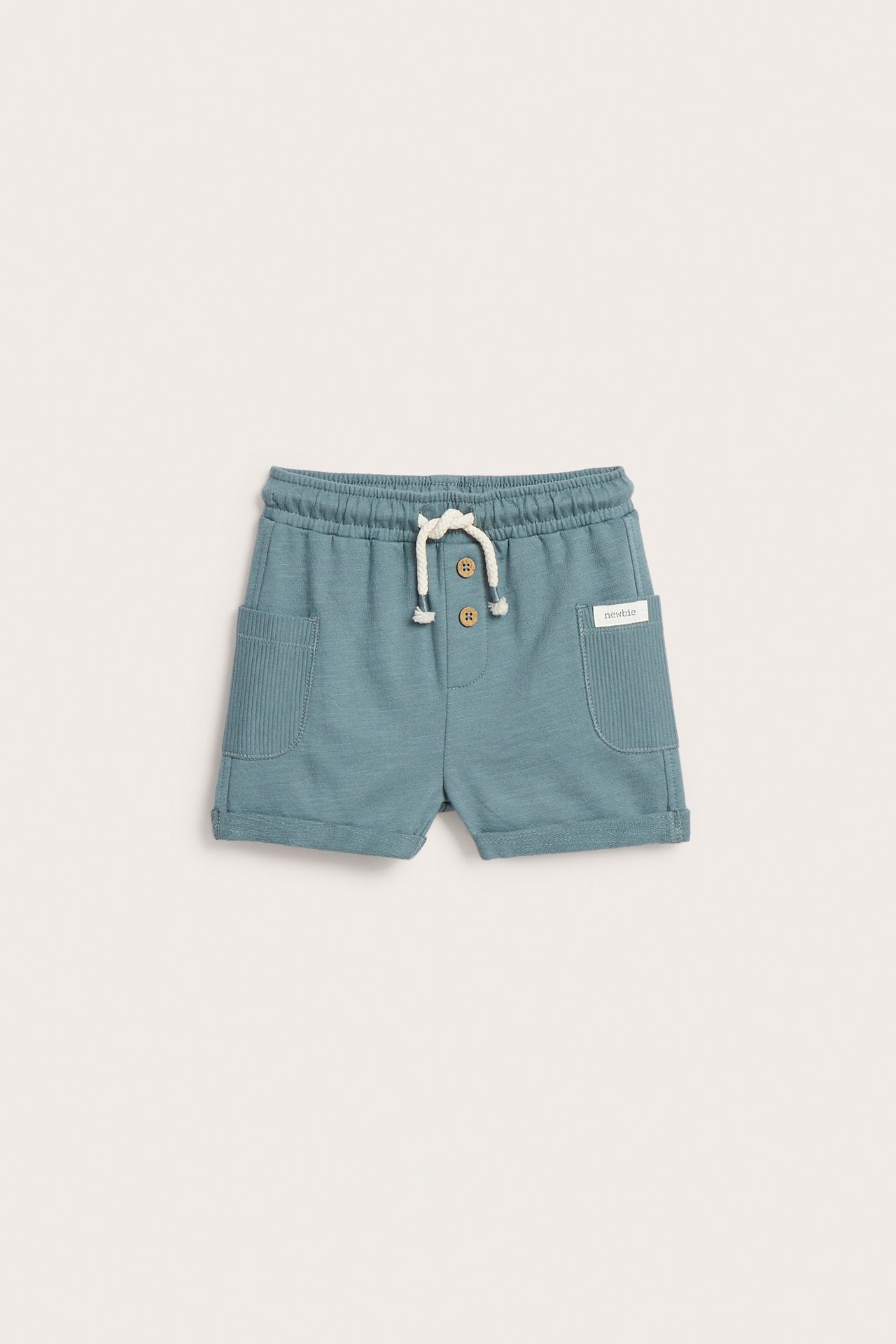 Front view of dark turquoise kid's slub jersey shorts with elastic waist, white drawstring, brown buttons, and ribbed pockets.